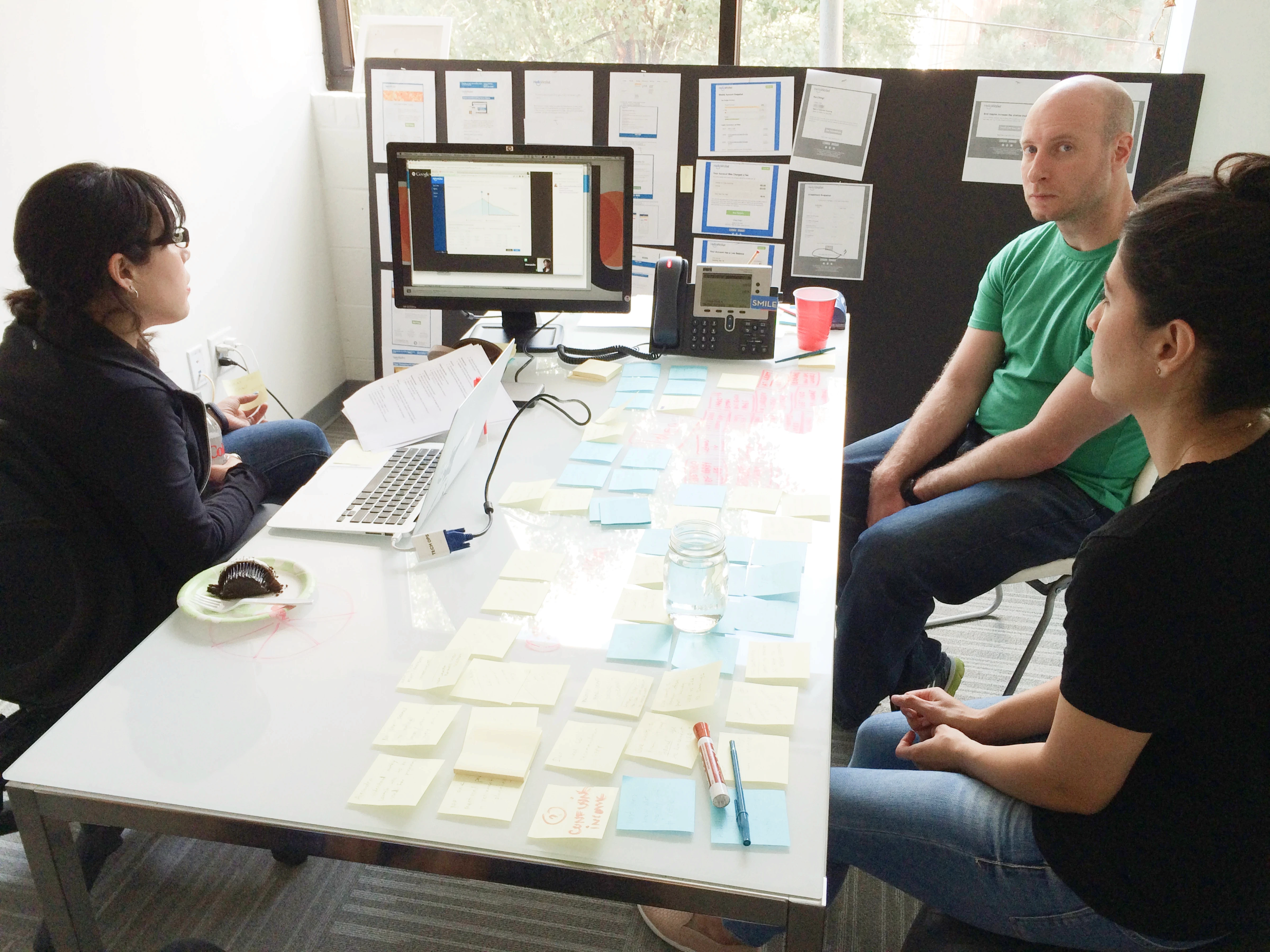 Team members sitting around a table in an office, watching a remote user research session.