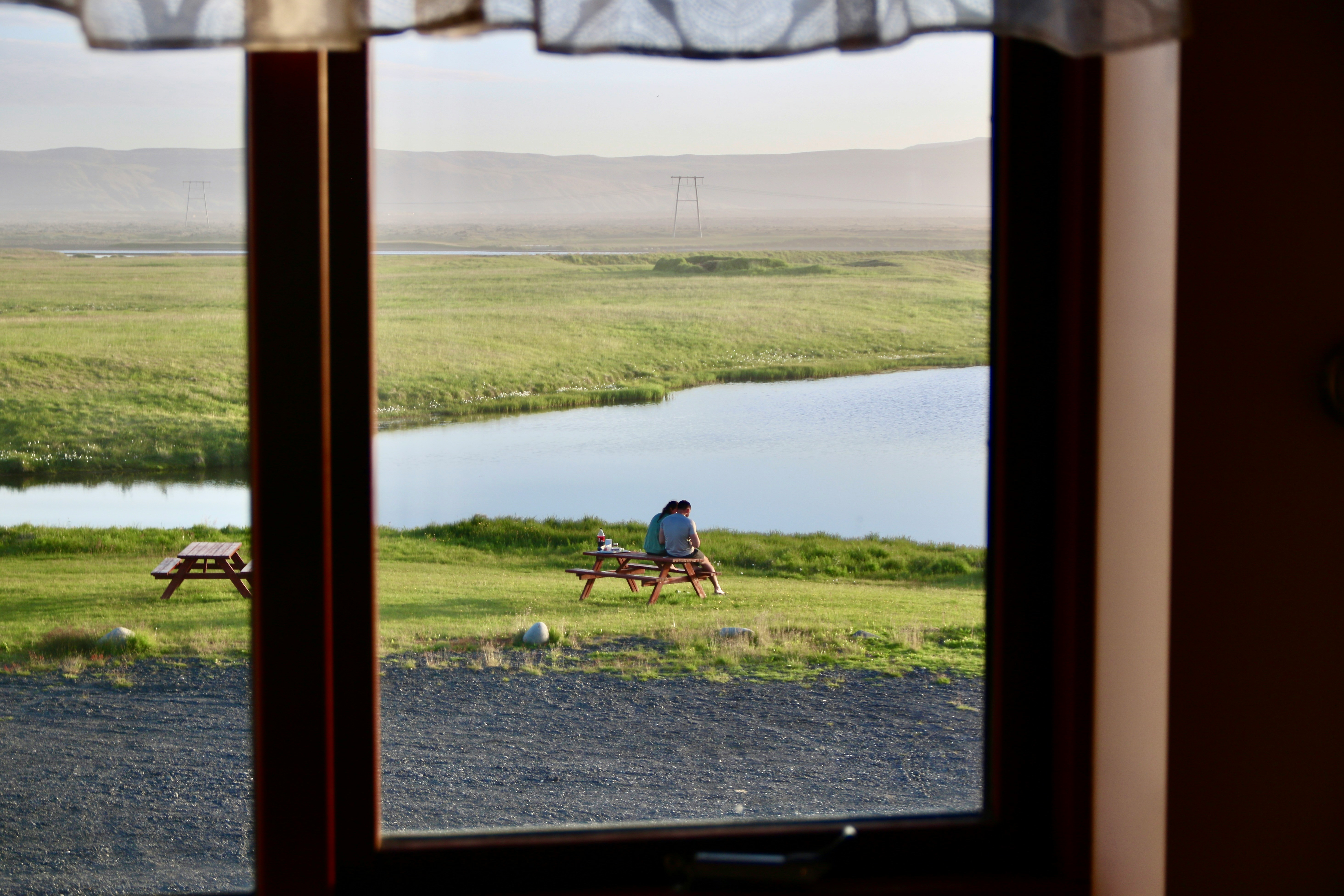 A couple sitting on a wooden bench overlooking a lake in Iceland.