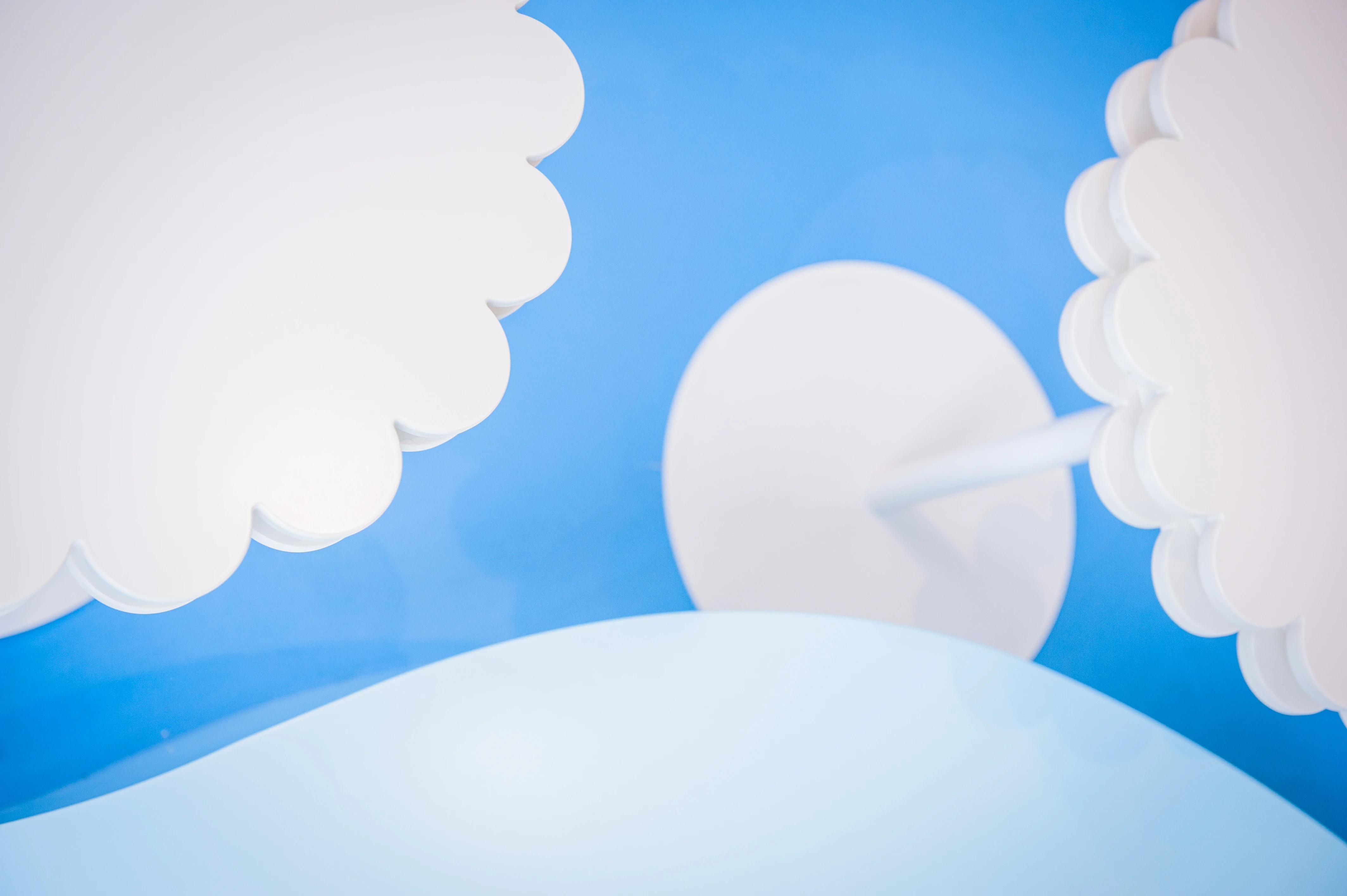 Detail of white cloud-shaped panels and a round table top against the sky-blue wall of the Alpro Leckerland pop-up.