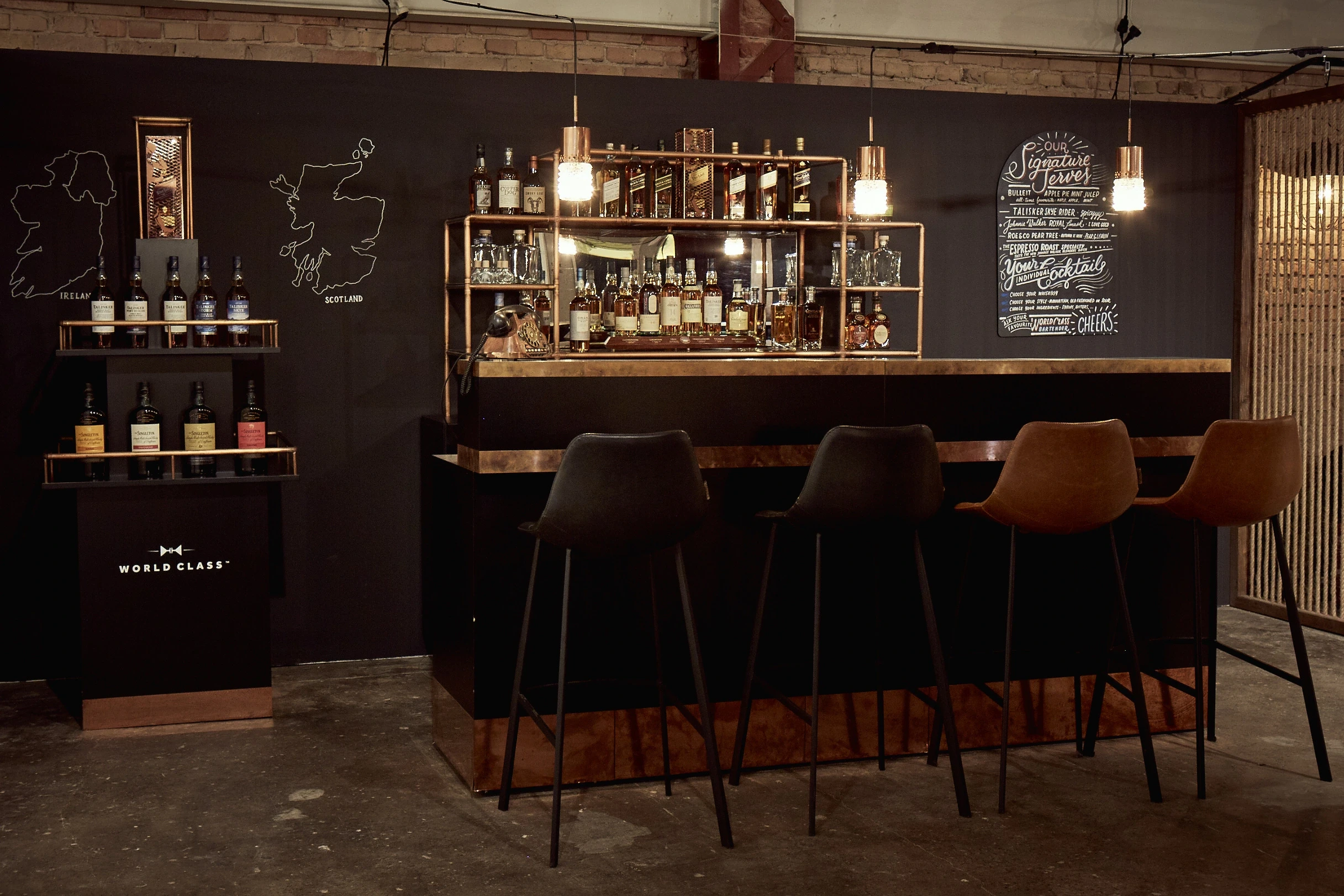 Whisky bar at DIAGEO BCB17 with leather bar stools, copper shelving with bottles, hand-drawn maps of Ireland and Scotland and a chalkboard cocktail menu.