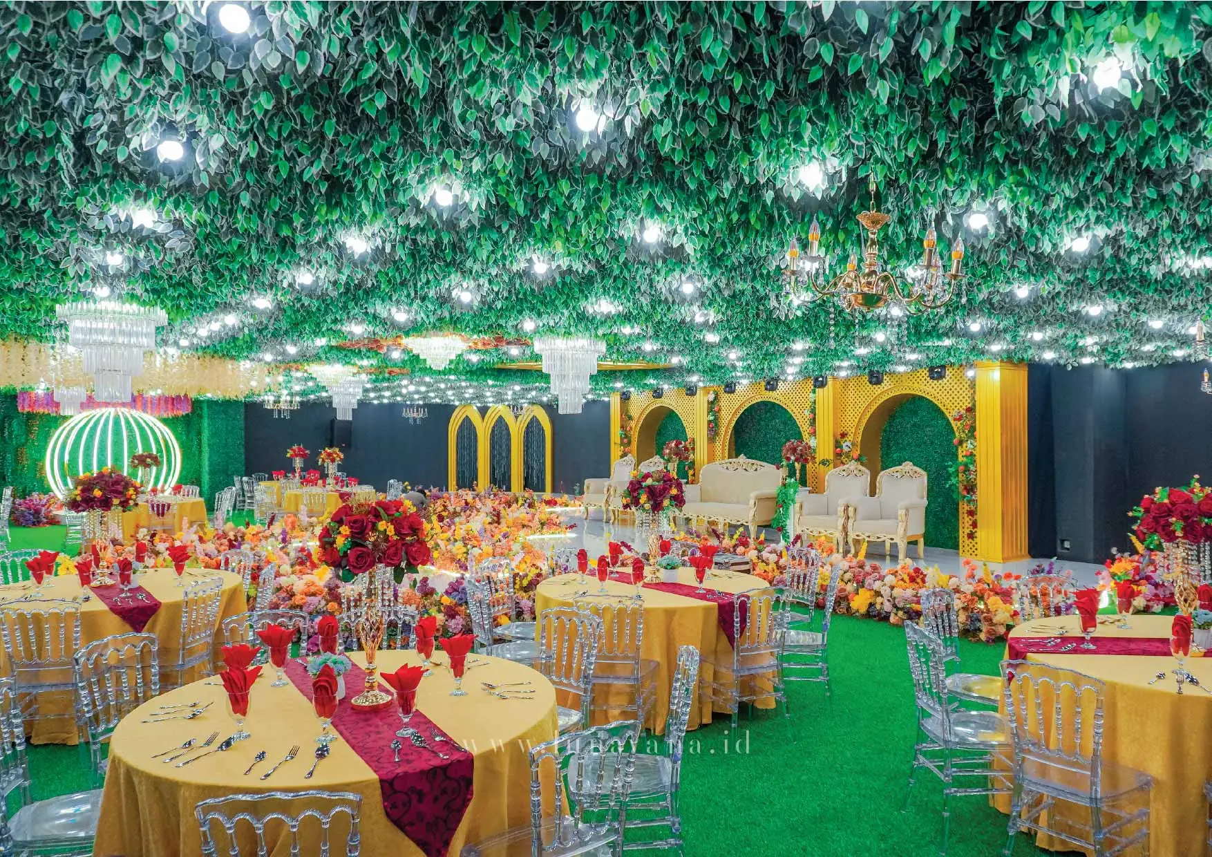 Interior venue Aruna Vana Events — pelaminan emas, chandelier, dan dekorasi bunga di Menara Pondok Indah, Jakarta Selatan