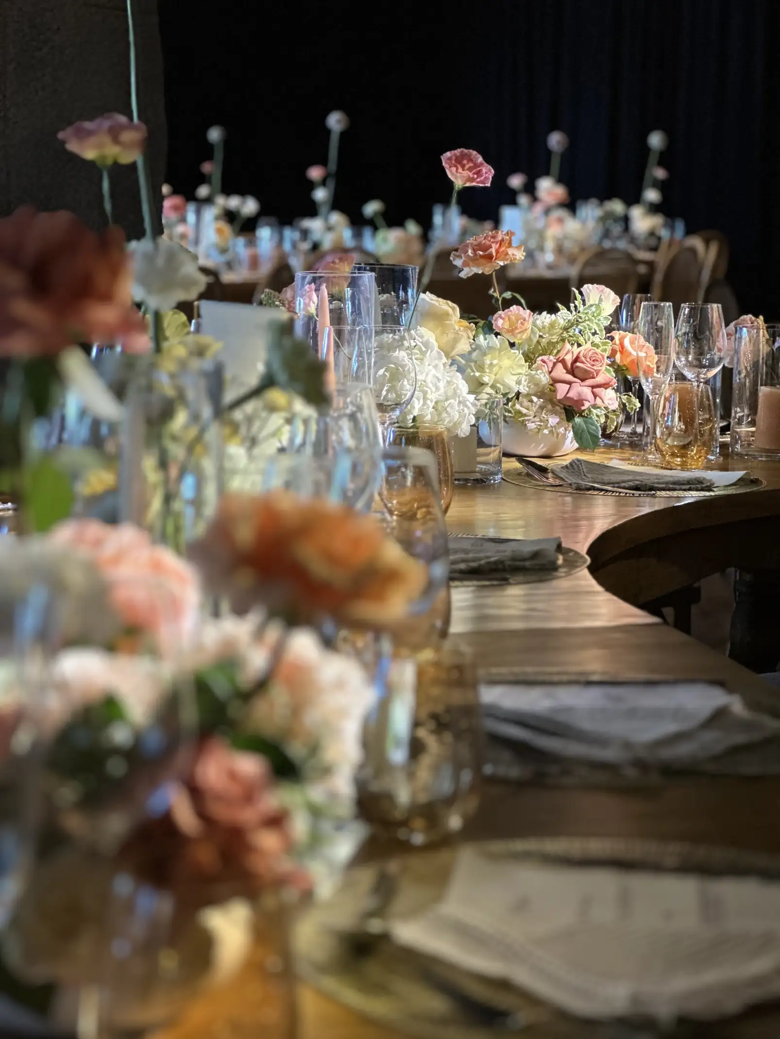 Centro de mesa floral con flores frescas en tonos neutros y cálidos, sobre mesa de madera natural.