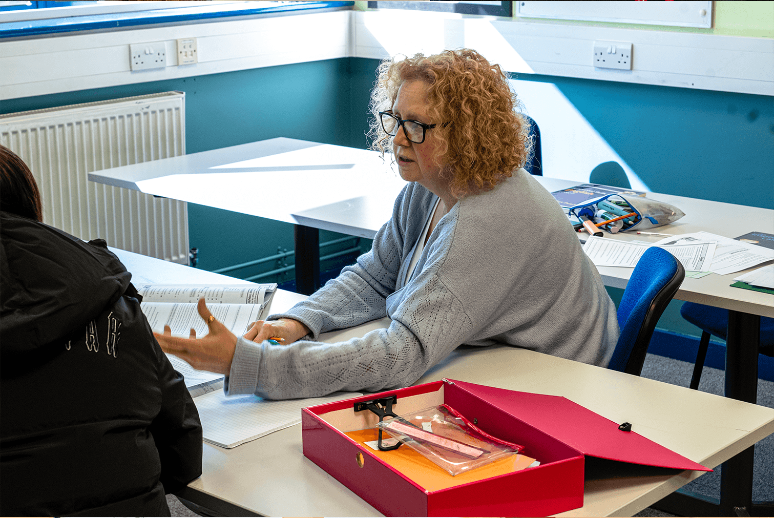 Mentor extending her hand to assist a student during a learning session at the centre