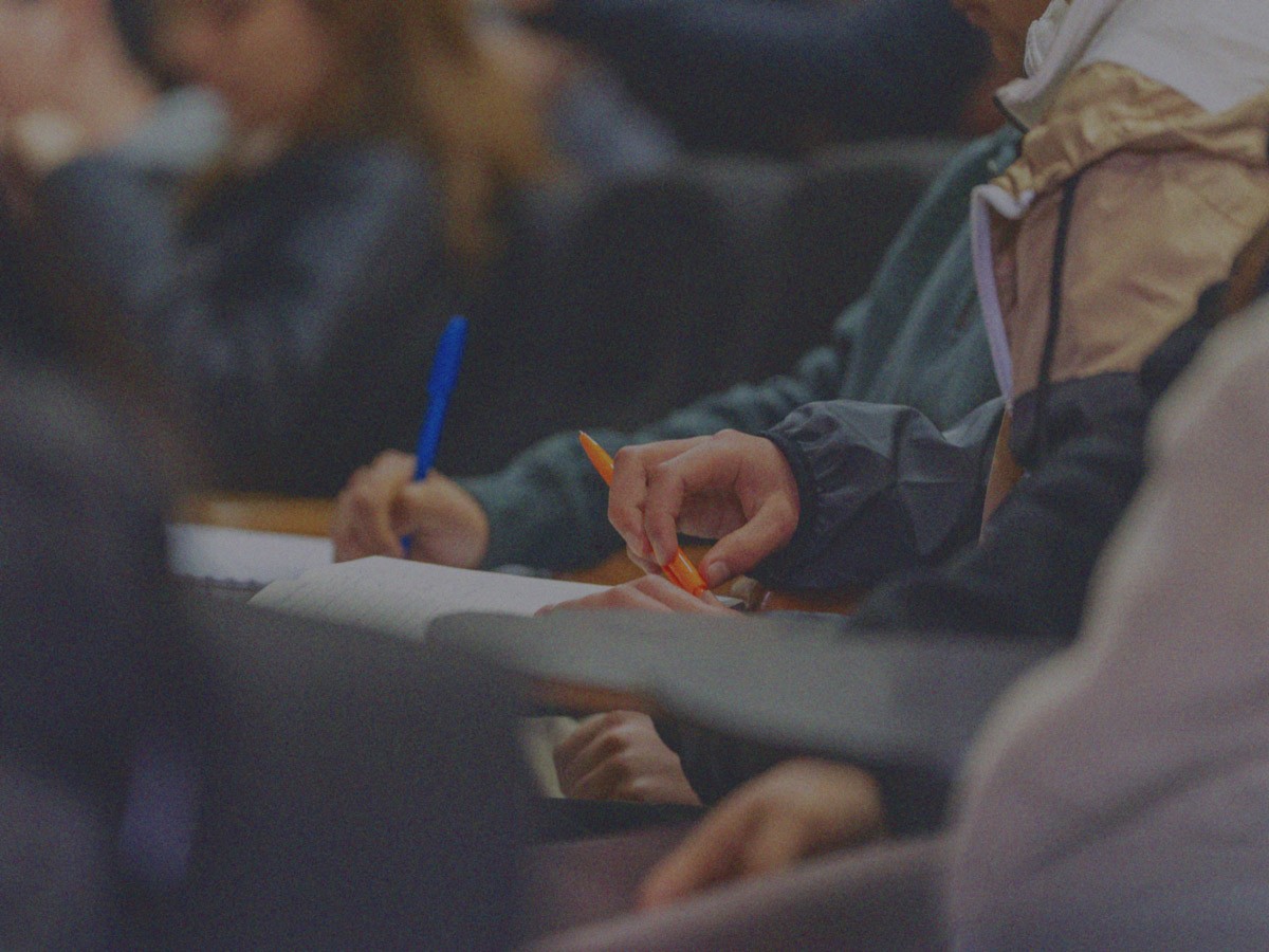 Manos de personas que toman apuntes, con lápiz y una libreta, en un evento realizado en la Región de La Araucanía por IdeaPaís.