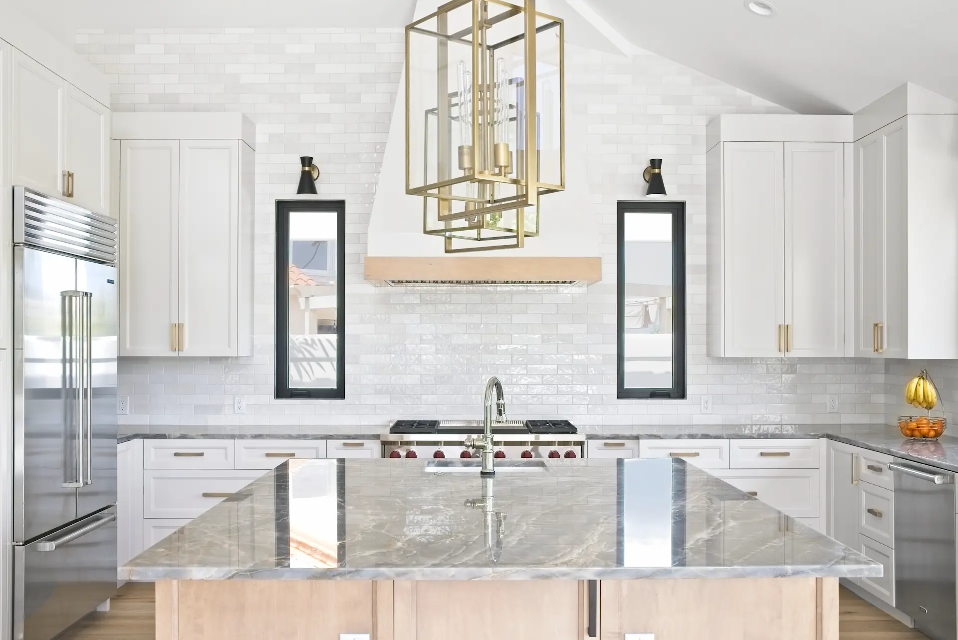 Wide view of the elegant kitchen overlooking the large island, with a focus on the oven, showcasing beautiful quartzite countertops and custom cabinetry in the Dana Point Full Remodel. Photo by Todd Huge.