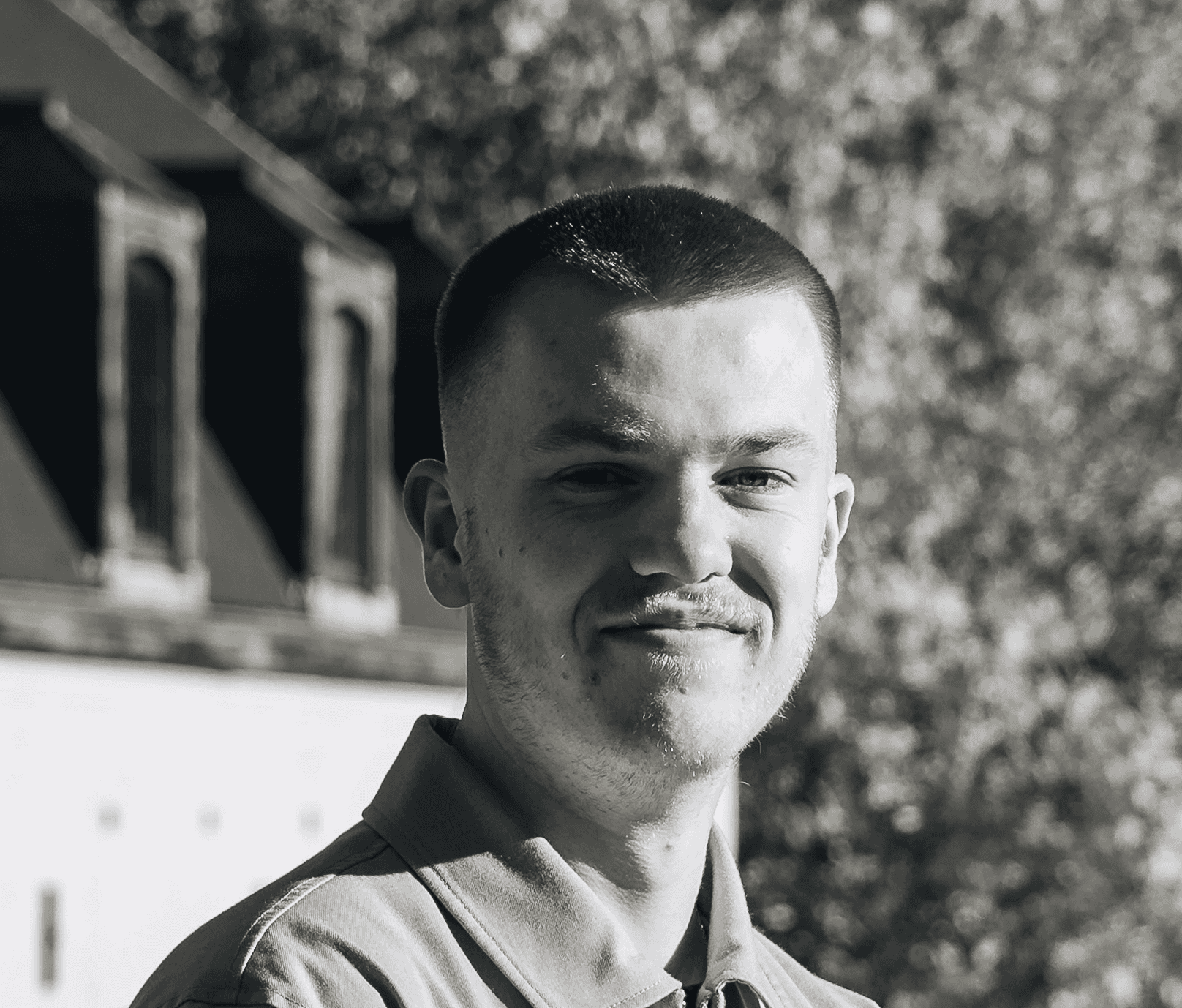 Portrait of a laughing person with curly hair wearing a white shirt