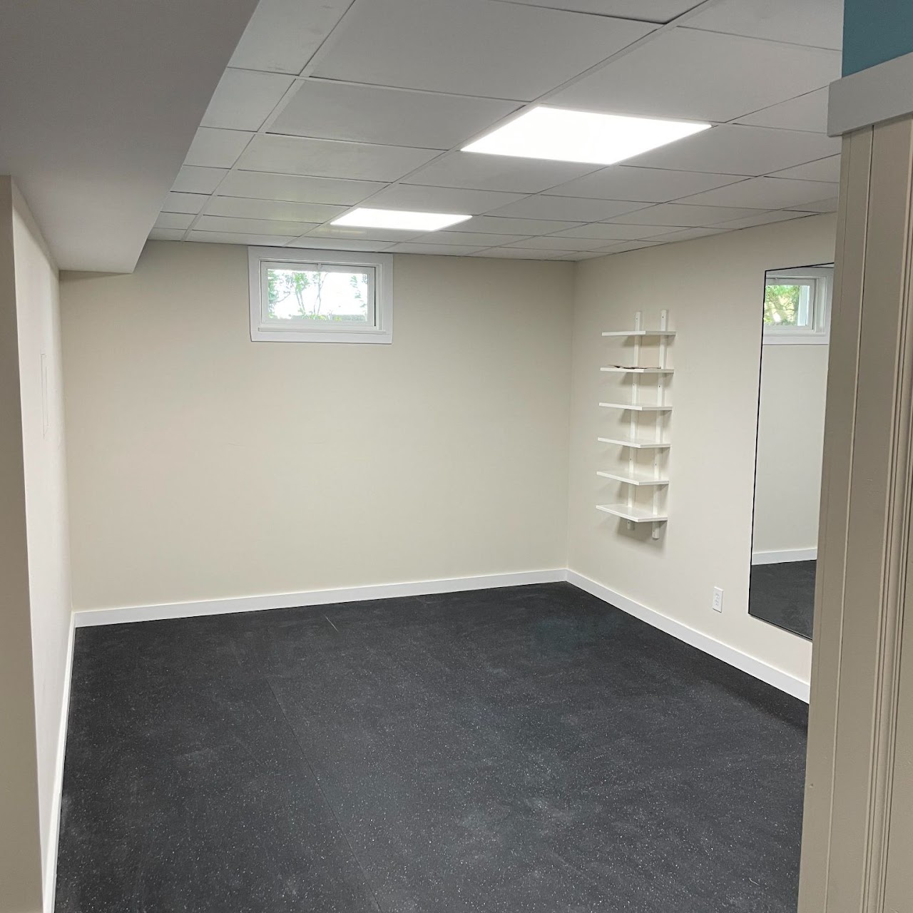 Finished basement room with carpet tile and bright white walls