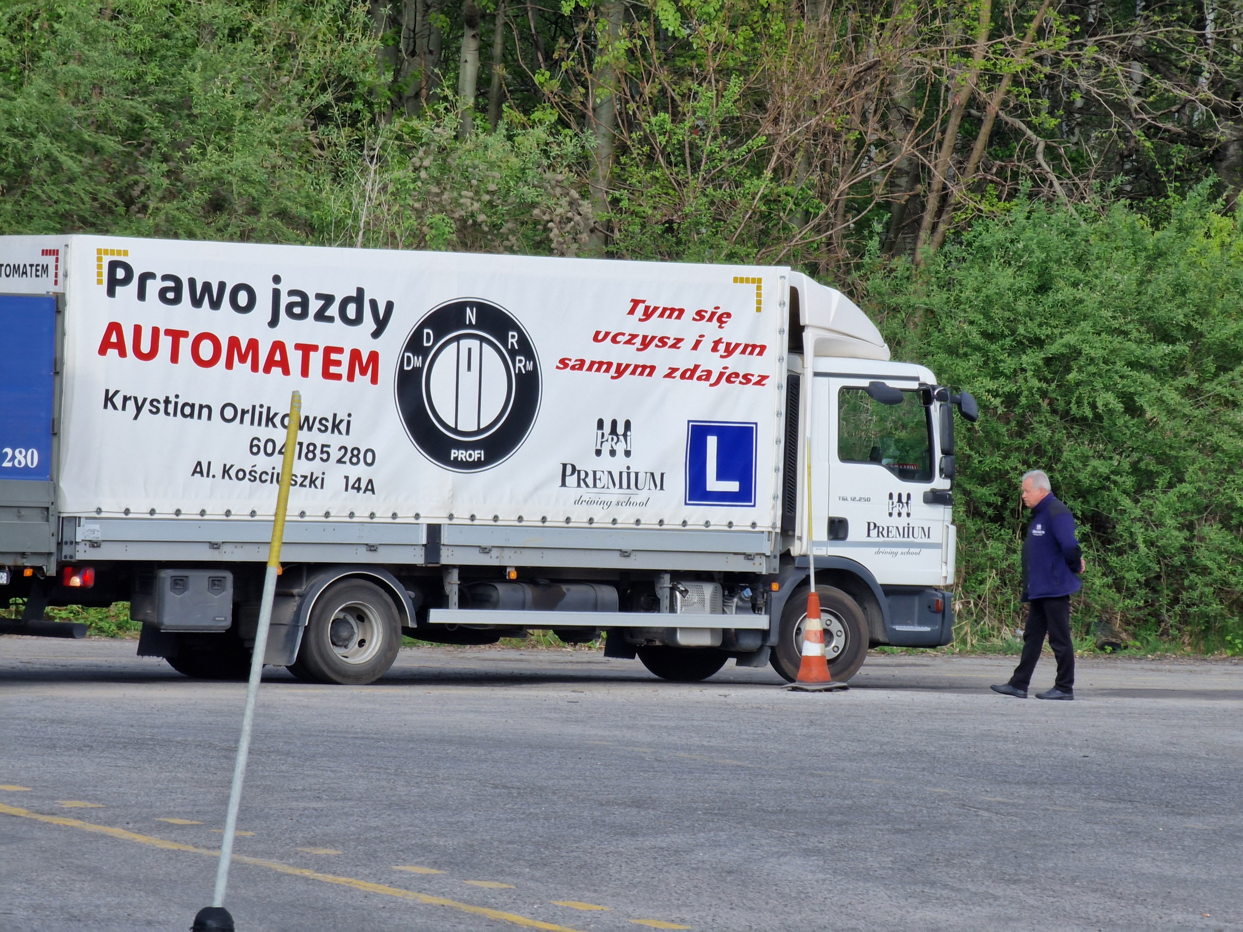 ciężarówka szkoleniowa OSK Premium z napisem „Prawo jazdy automatem” na tle zieleni