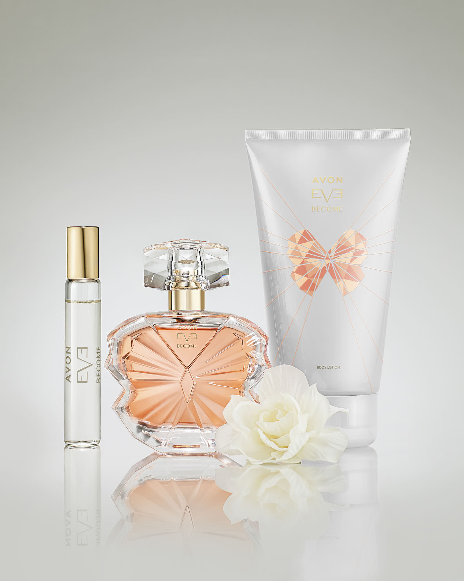 Three fragrance products are arranged: a large bottle, a small vial, and a tube, all featuring floral designs.