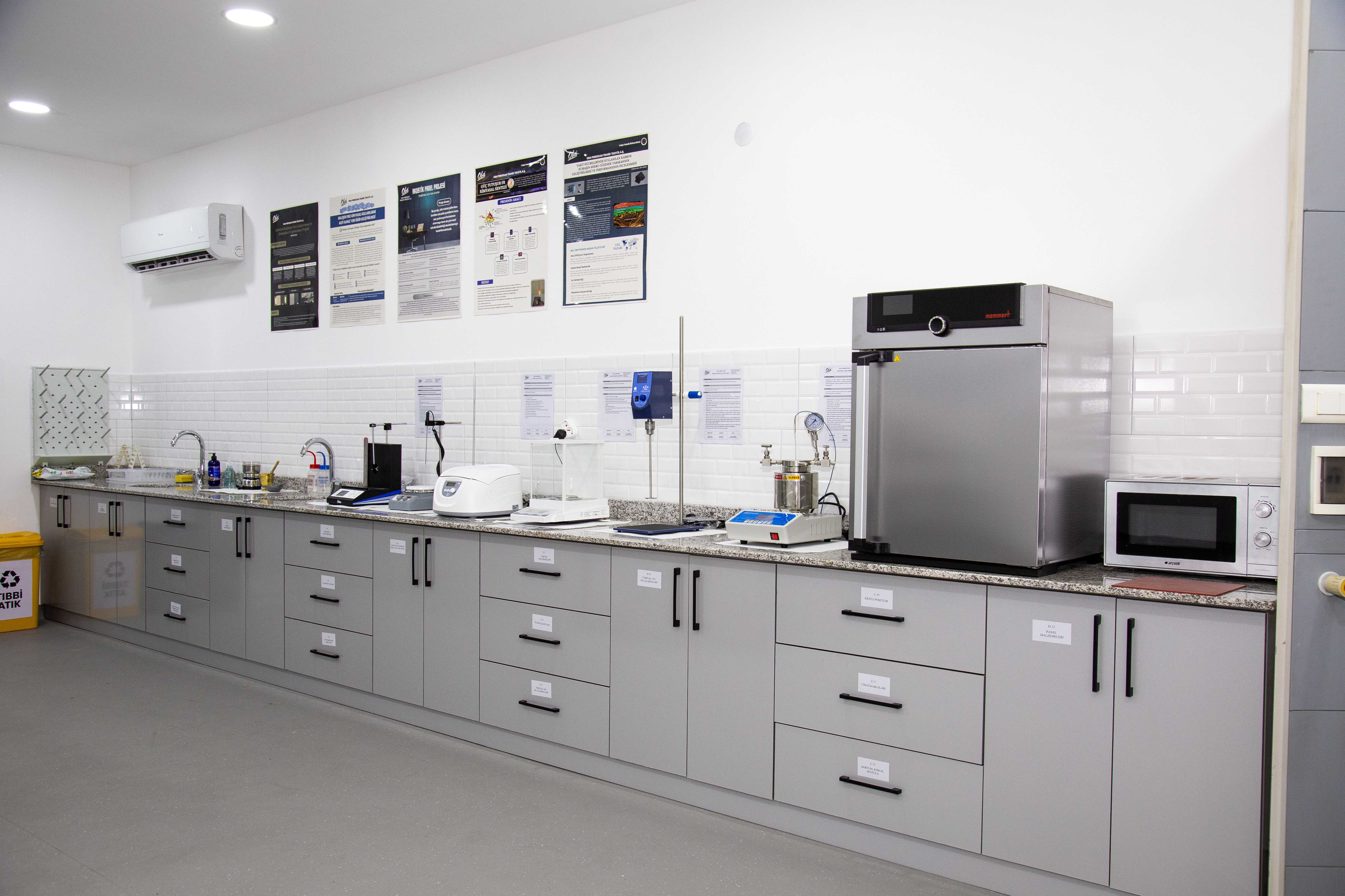 A man and woman sit on beige chairs in a modern room with a red paneled wall. A red pendant light hangs above a wooden coffee table between them.