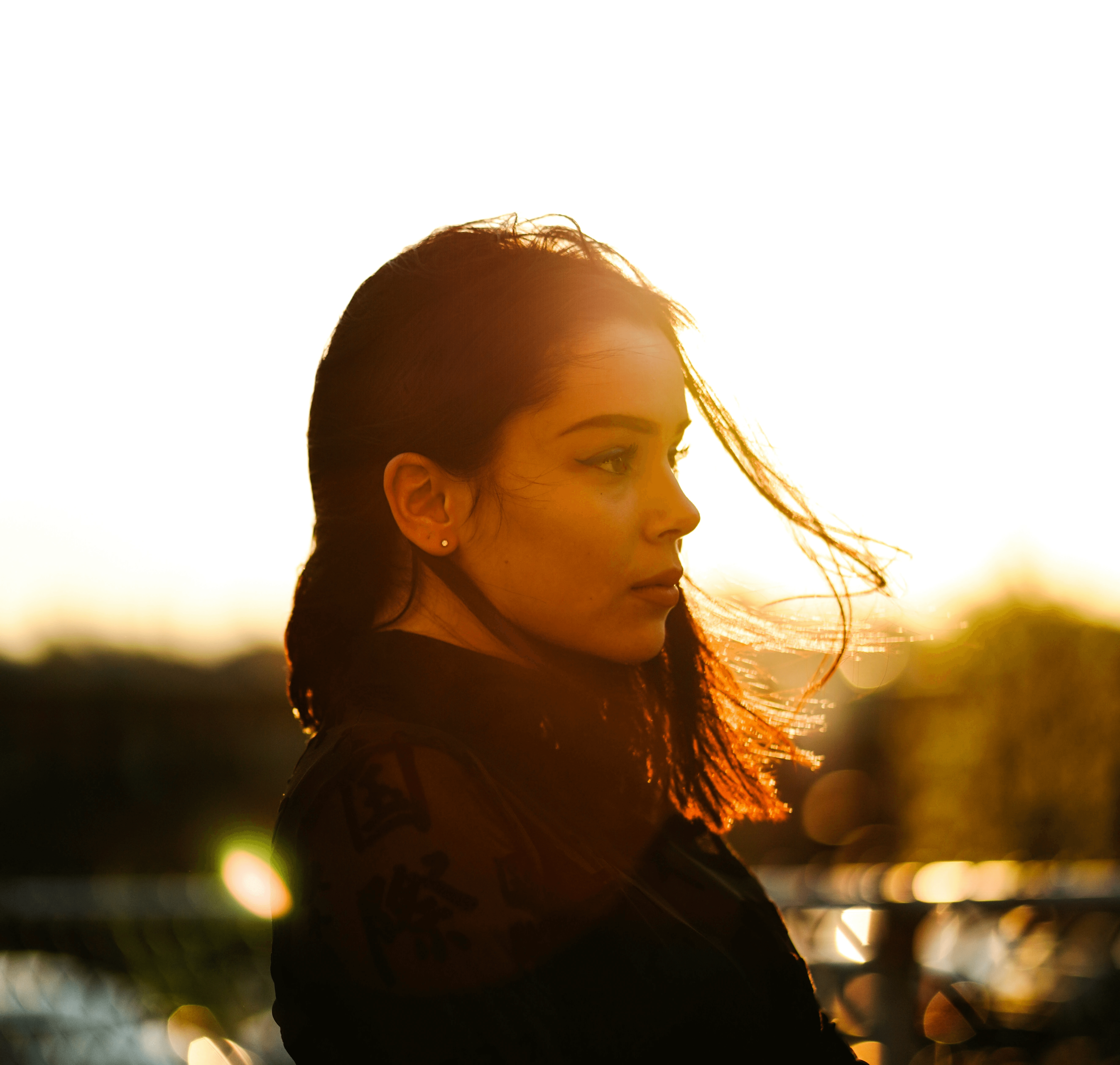 woman standing in front of gray metal fence during sunset