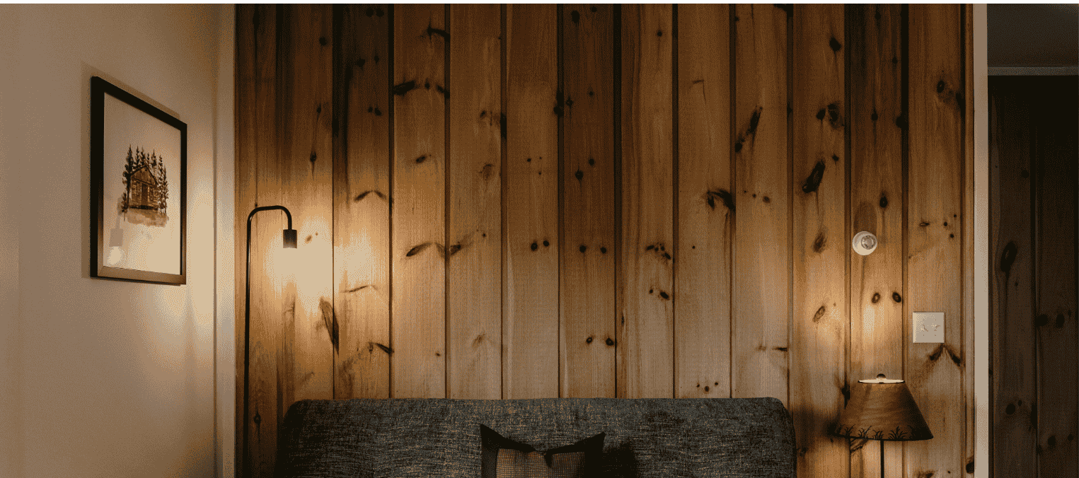 Interior of an intentional living space with warm, vertical wood-panelled walls and modern lighting in a Strawtown home.