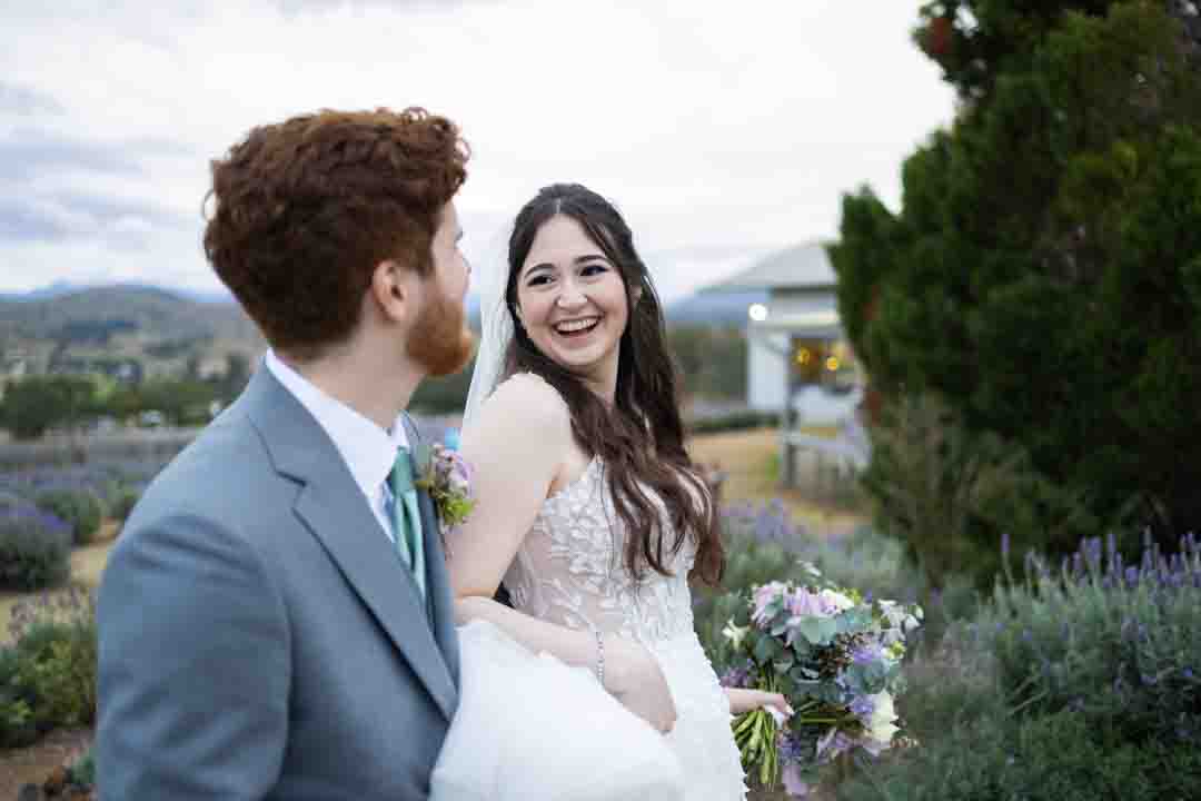 Bride laughing at groom as they walk through a lavender field