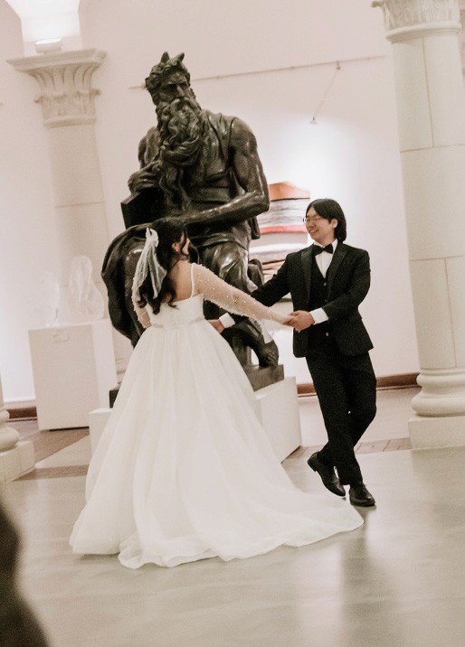 dallas biblical arts museum wedding bride and groom holding hands and spinning in front of art at the couples' portaits.