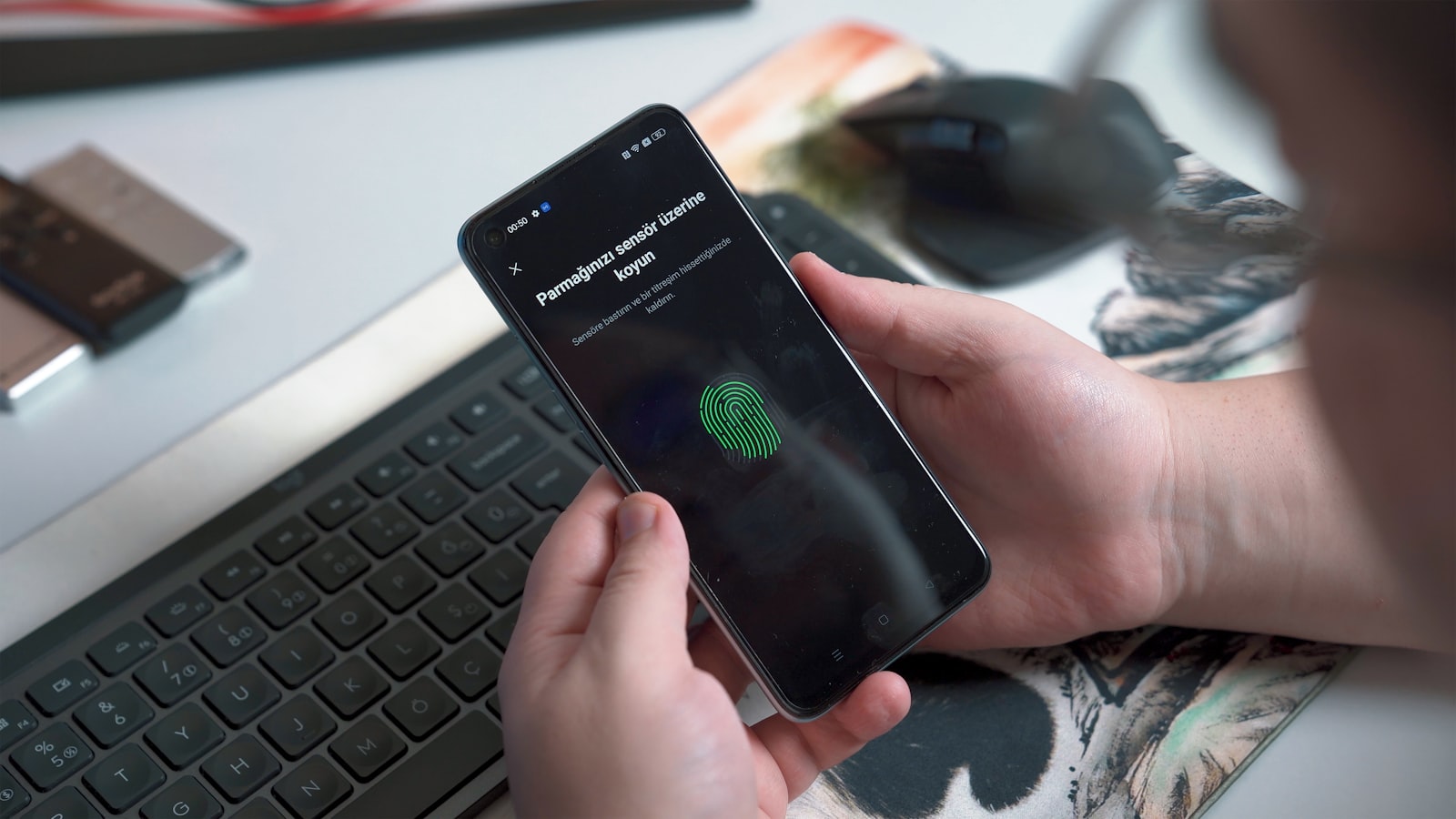 Approving a sign-in with a fingerprint prompt on a phone beside a keyboard