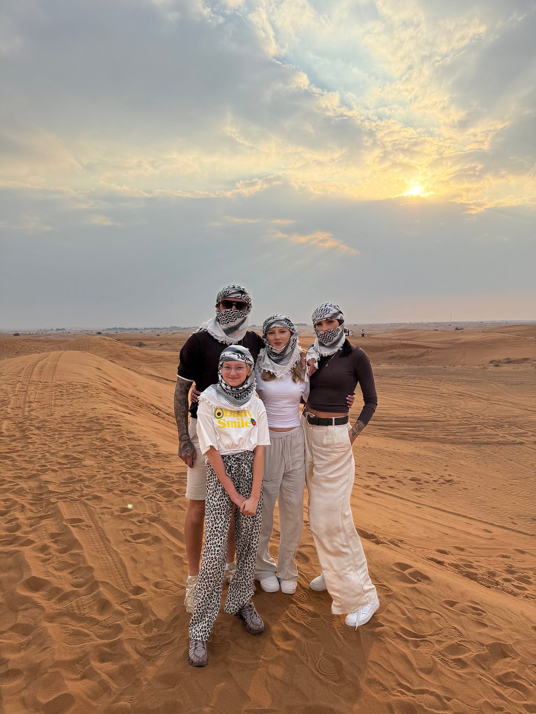 Family posing with falcon beside Can-Am Maverick X3 dune buggy during Dubai desert safari with Dune Quest Tours