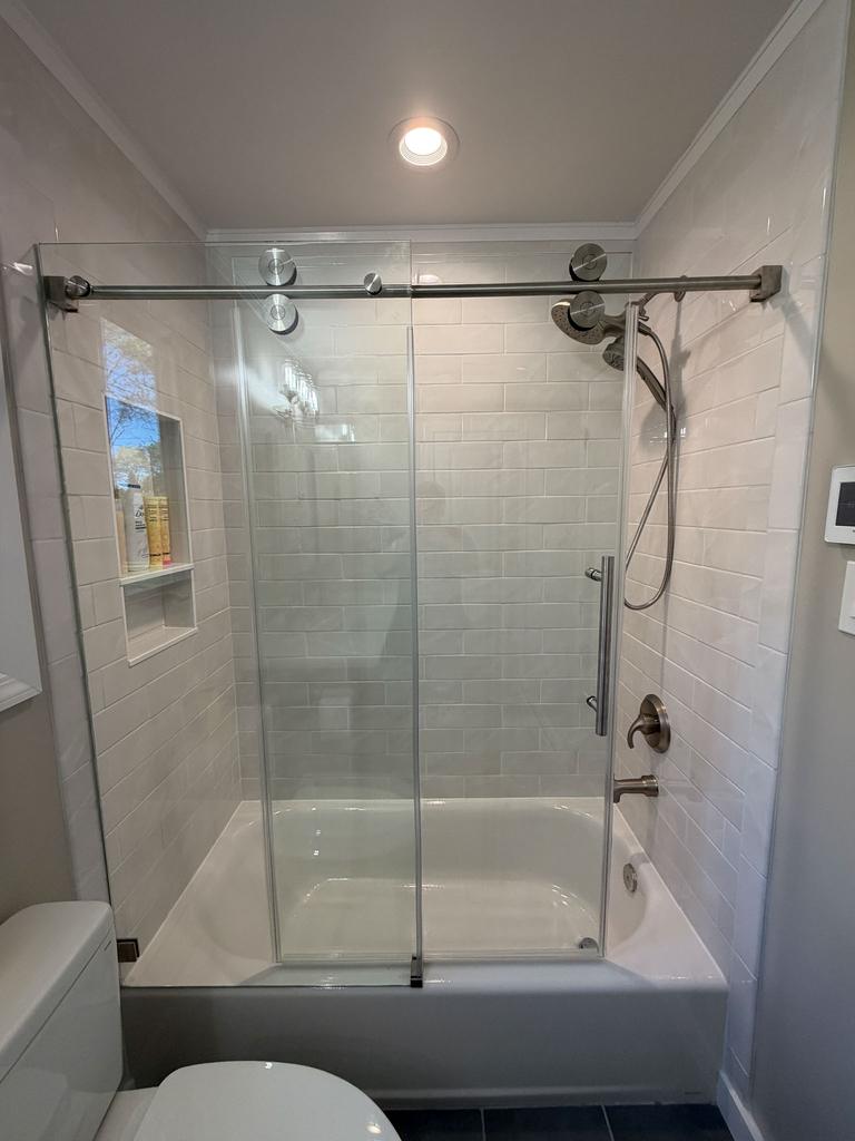 Tiled tub and shower combination with a frameless glass sliding door