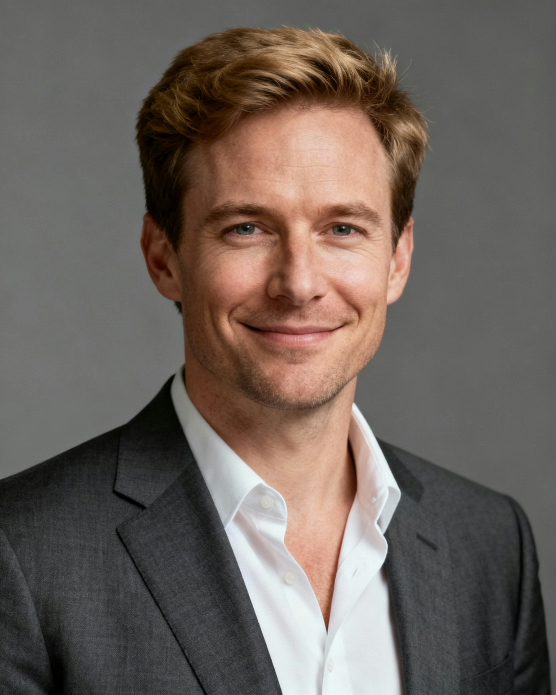 A professional portrait of a man in a suit and tie, smiling slightly against a neutral background.