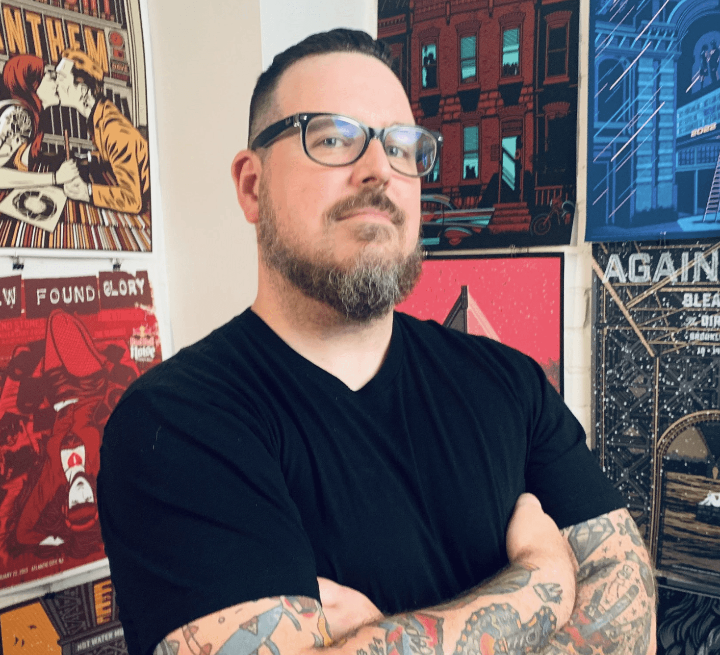 man with glasses in front of poster wall
