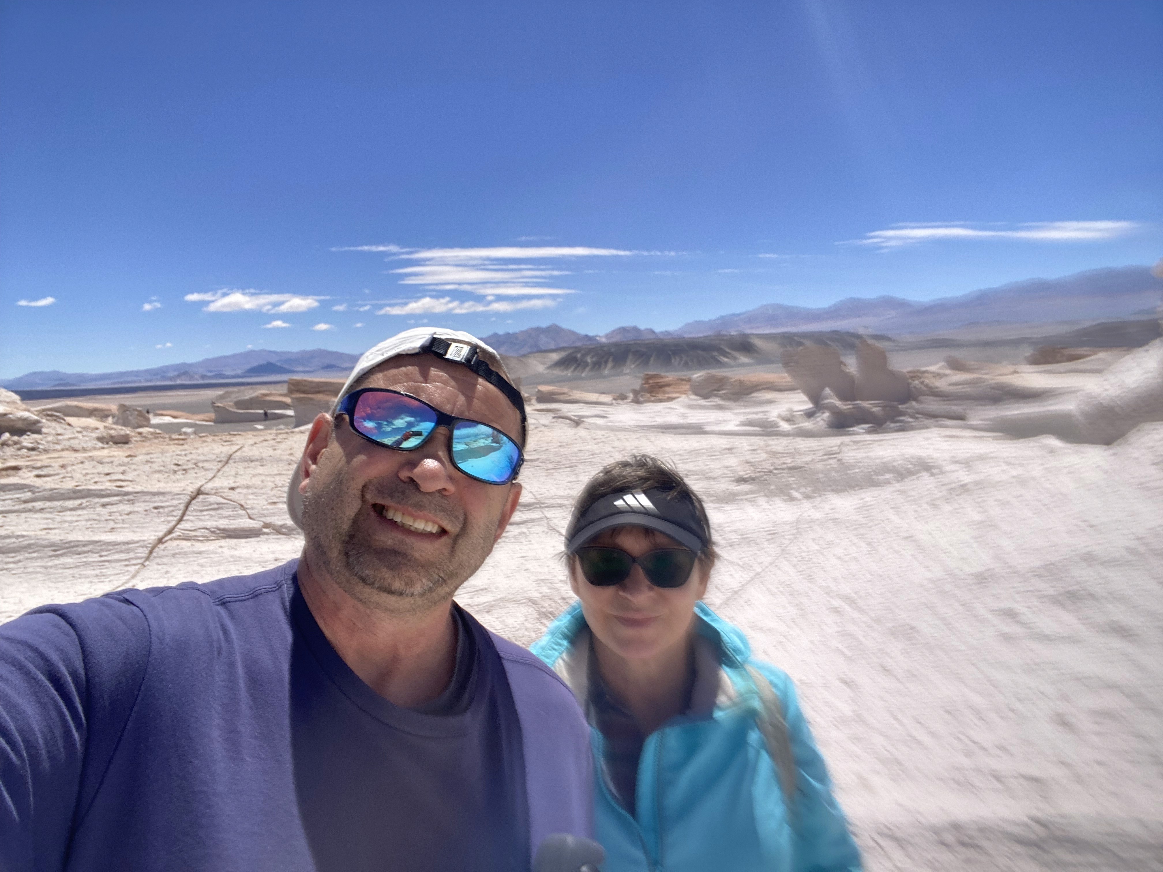 Mujer sentada sobre un tronco frente a una cascada doble en un bosque frondoso de Argentina.
