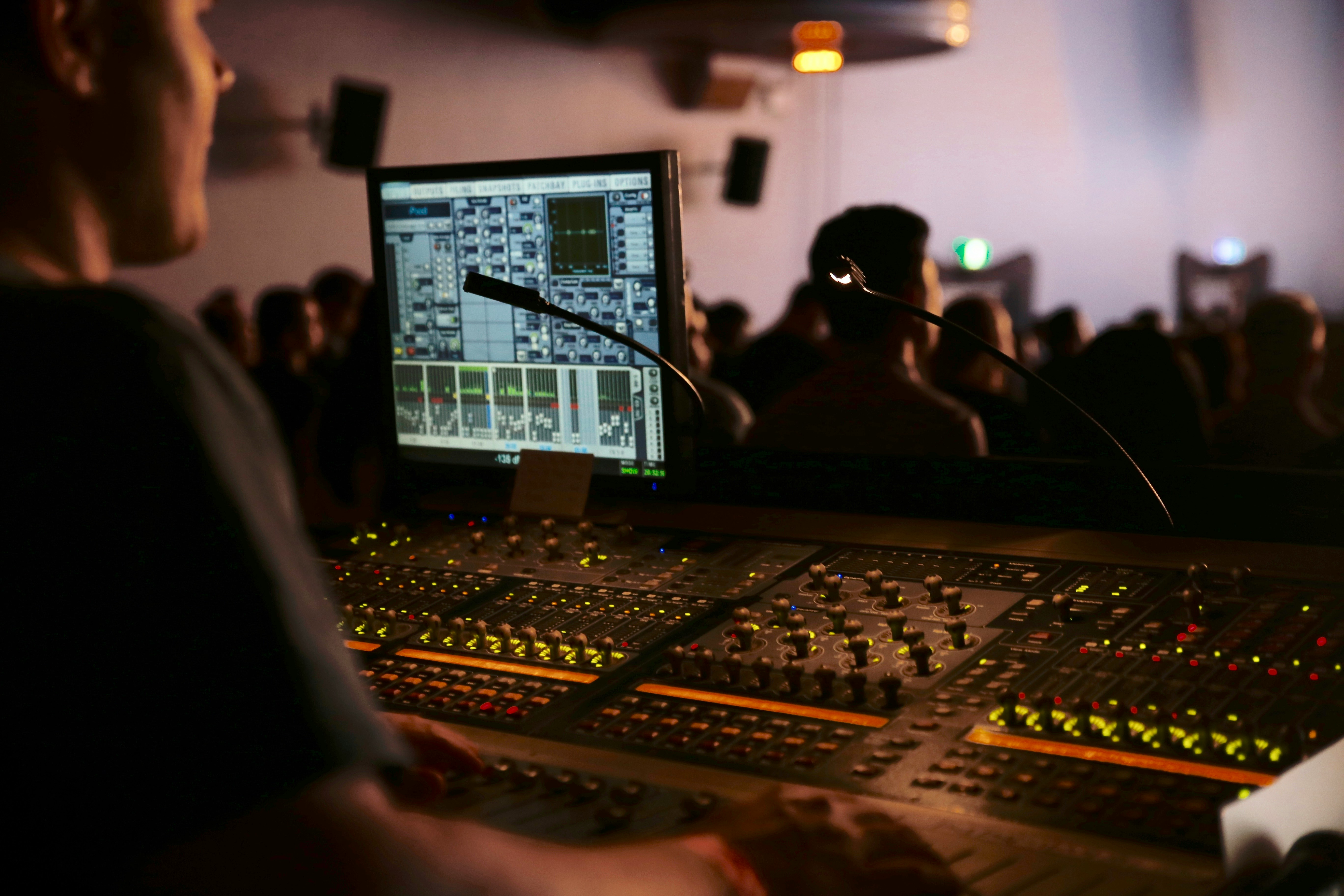 Sound mixer board and screen with audience visible.