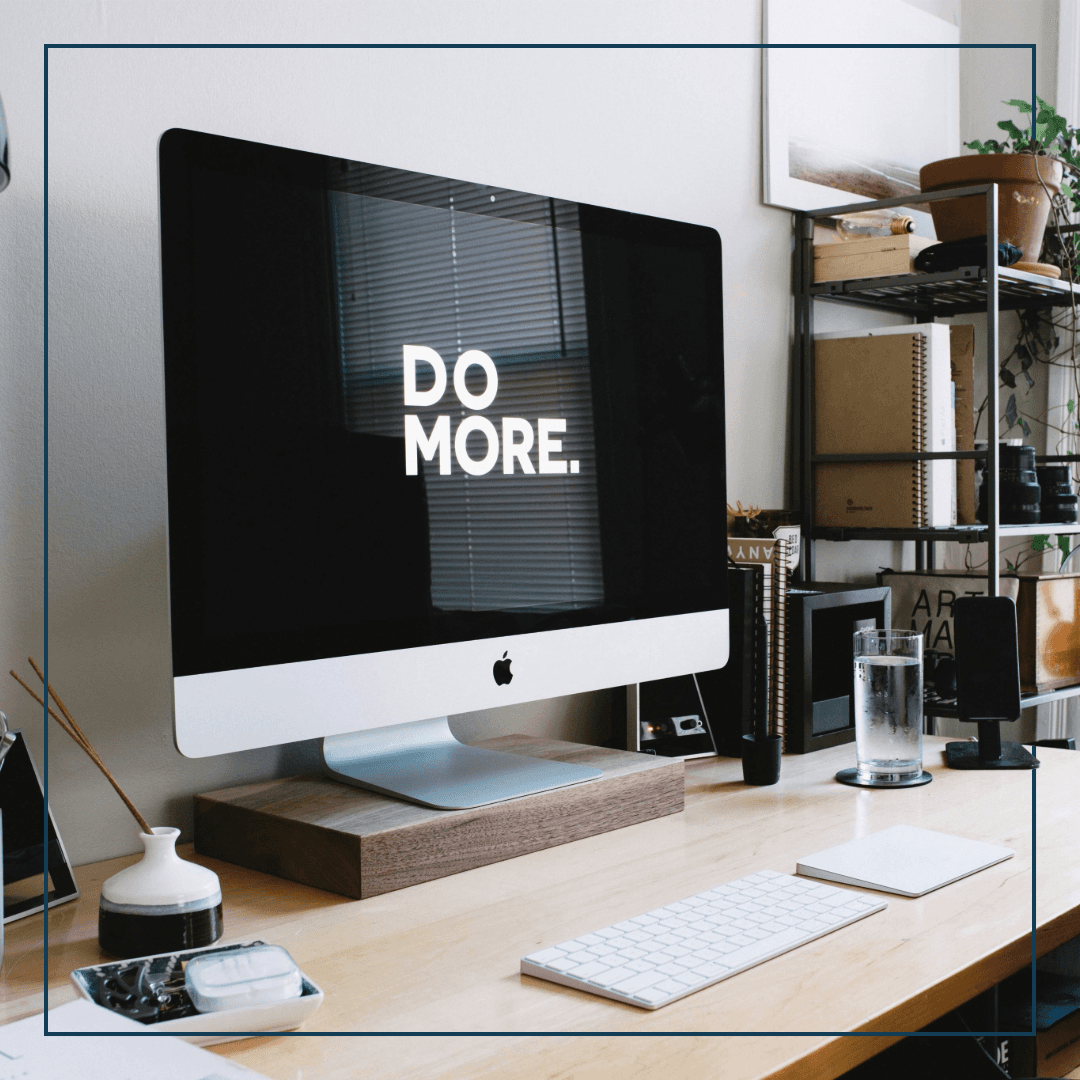 Ein Schreibtisch mit einem großen iMac auf dessen Bildschirm "Do More" steht