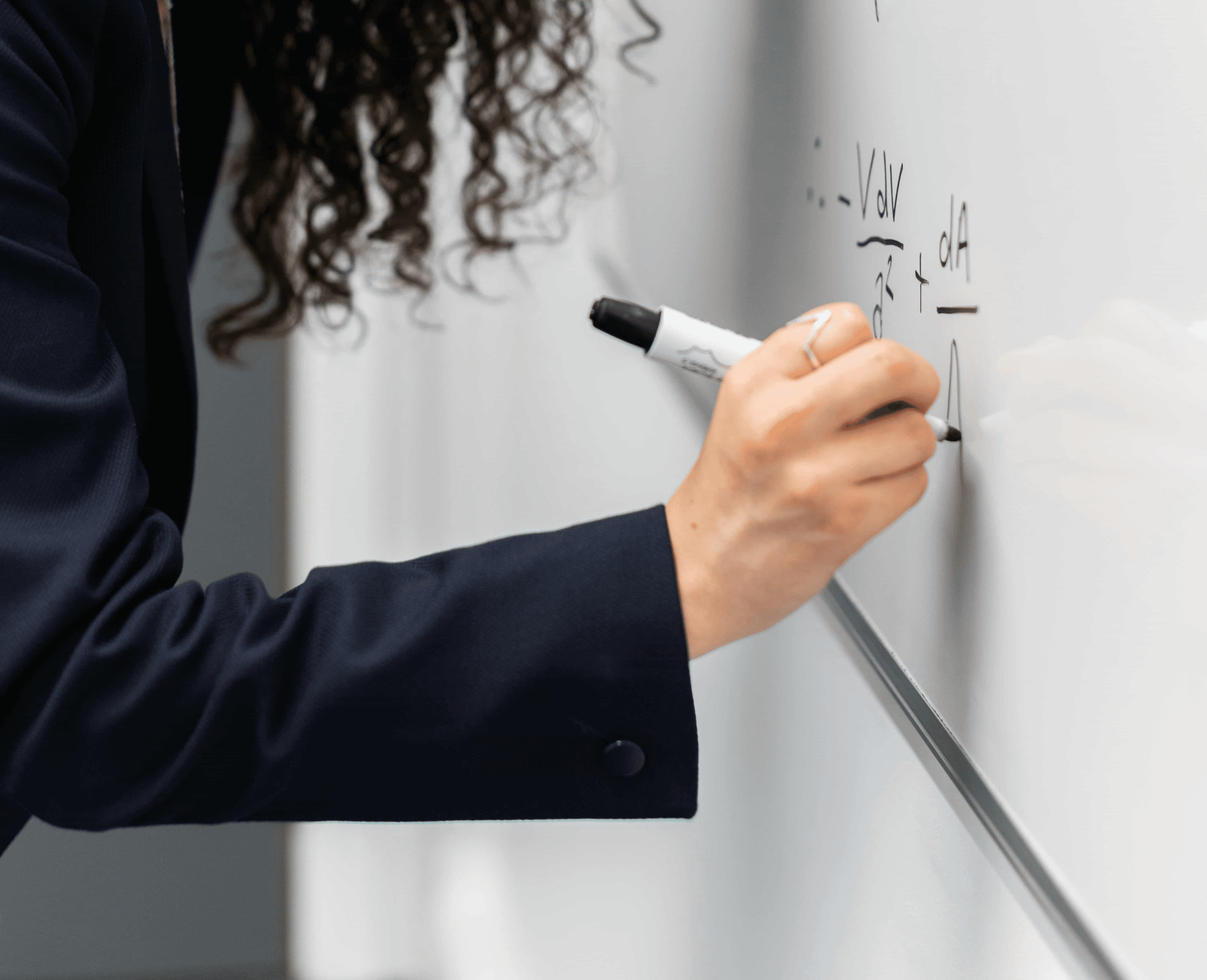 A winding road cuts through rocky terrain, surrounded by patches of green grass and illuminated by sunlight.