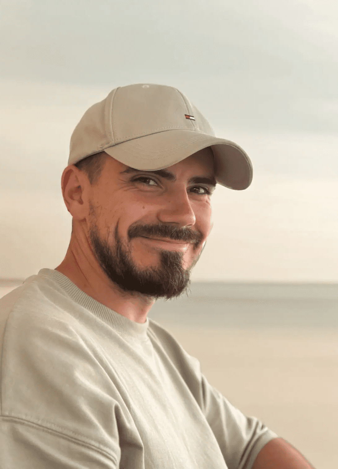 A smiling hadnsome young man, wearing a cap