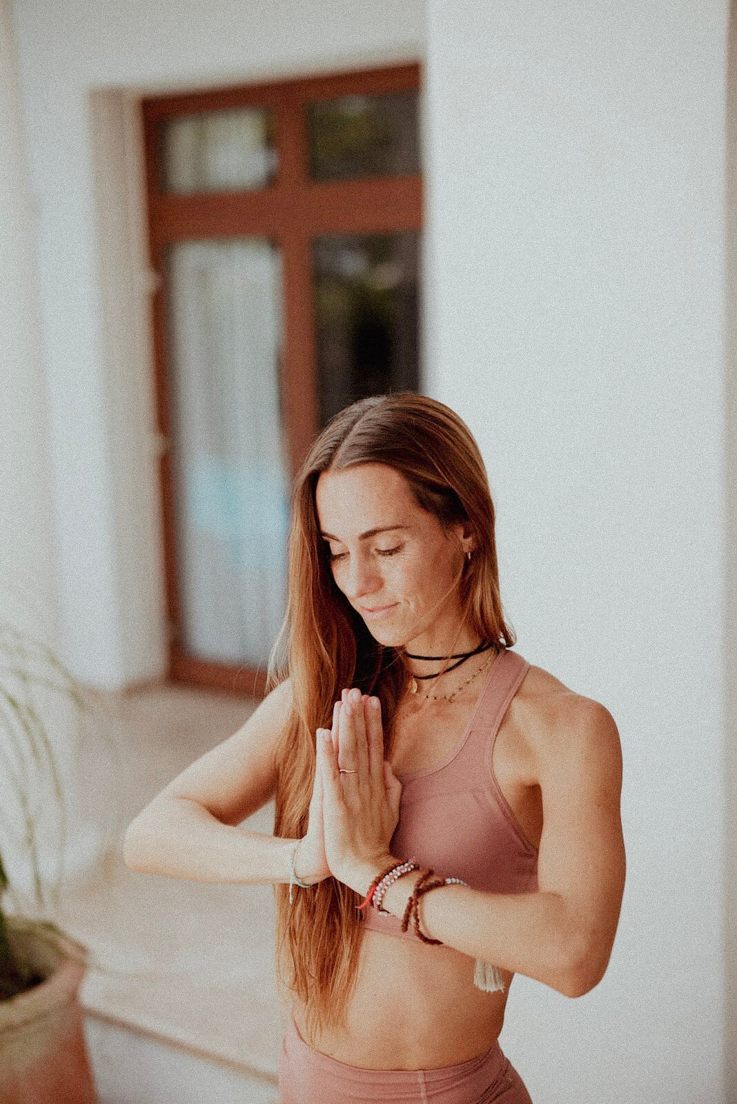 Persona en postura de meditación con las manos juntas en un espacio interior tranquilo.