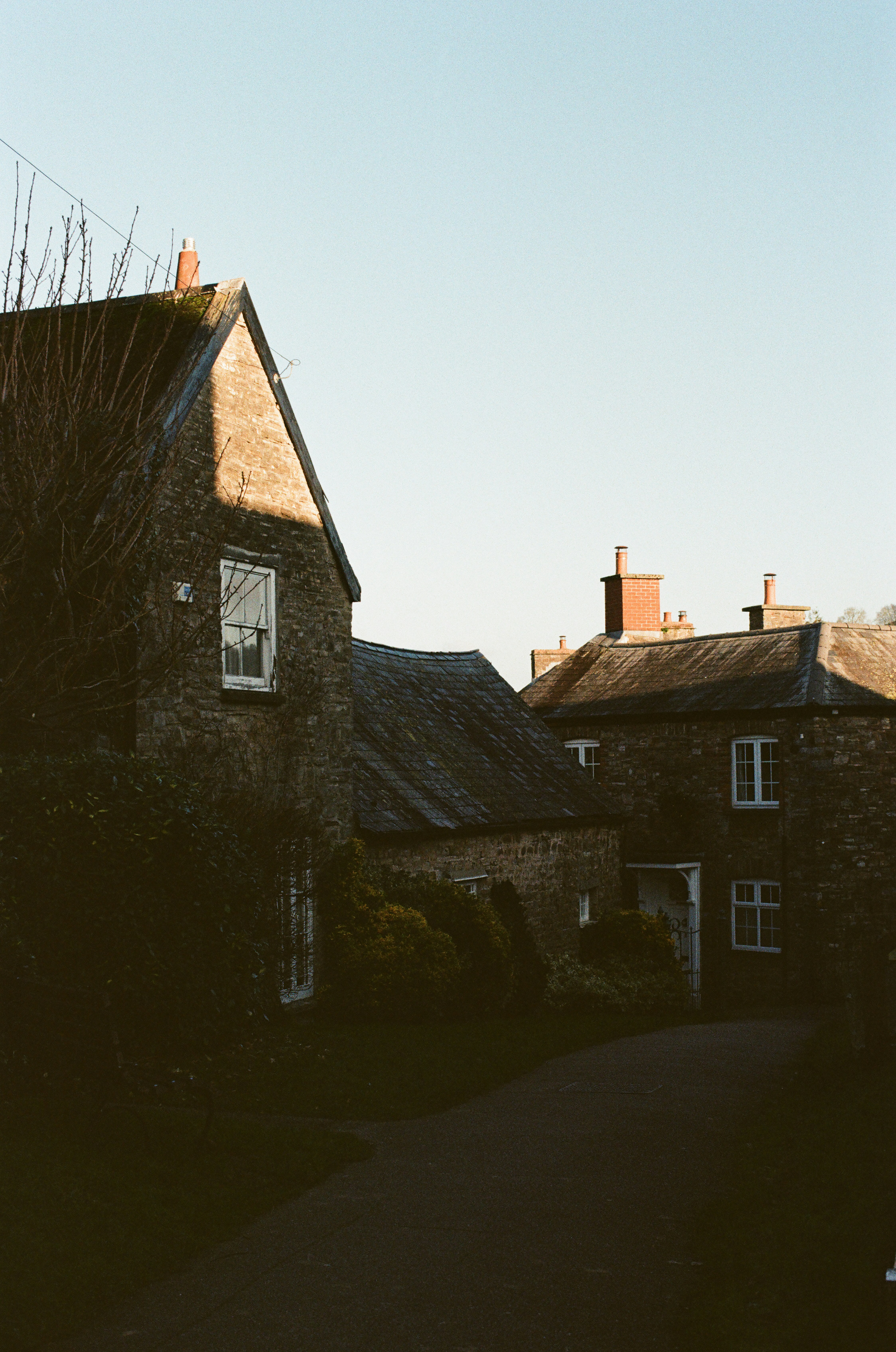 Stone houses line a quiet street under a clear sky.