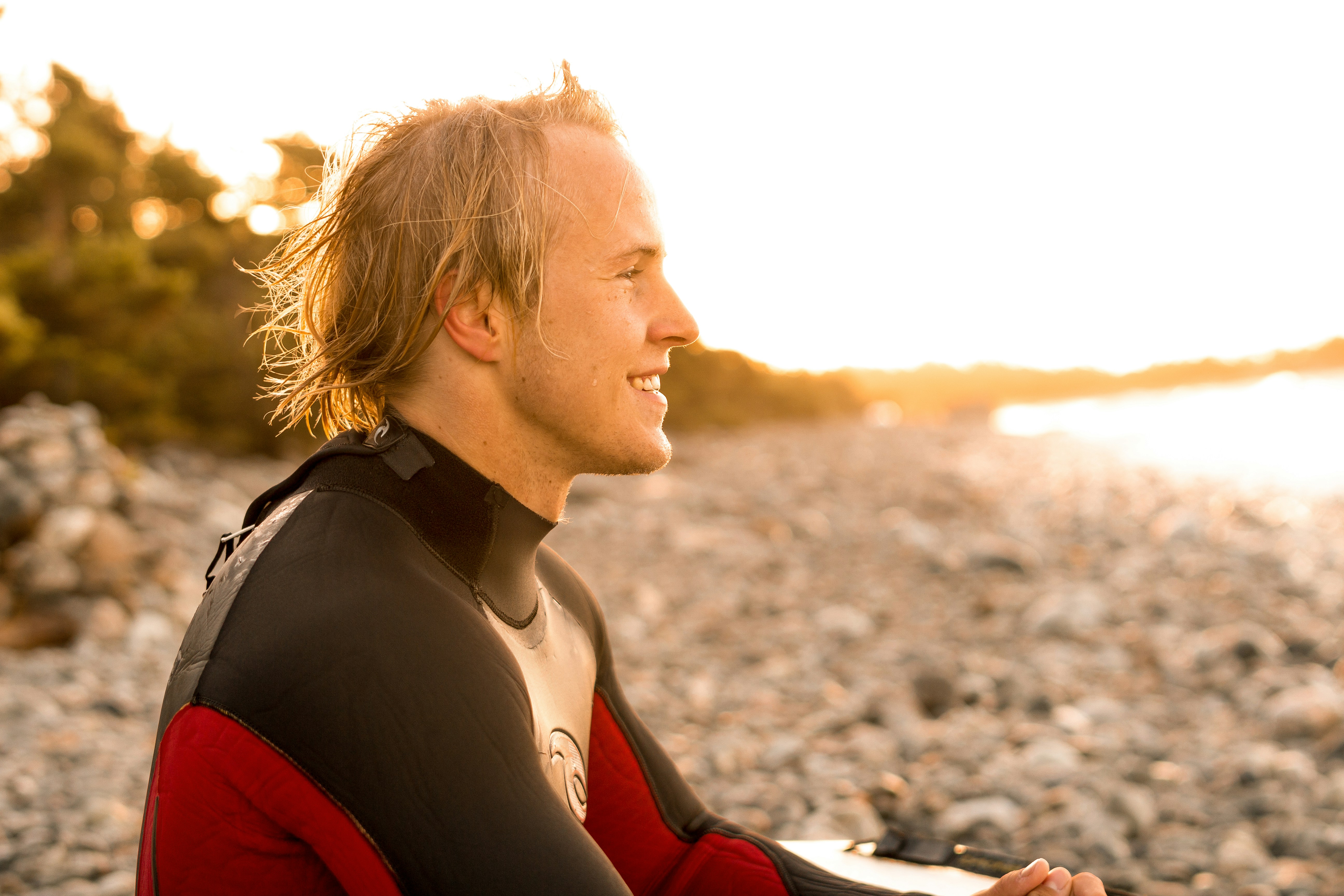 smiling man wearing wetsuit facing beach