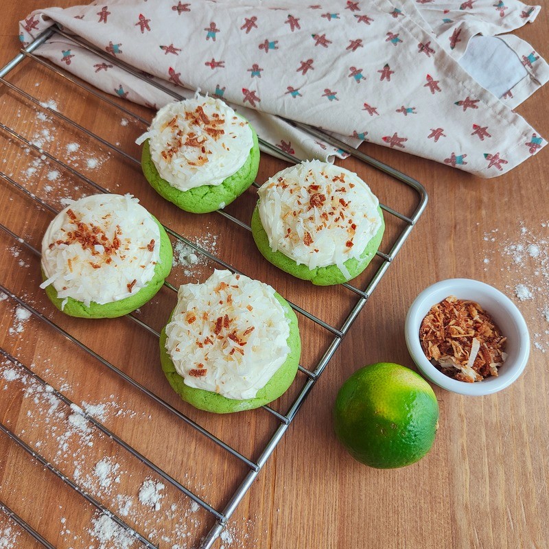 Freshly baked mojito cookies on a tray held by a baker in a café.