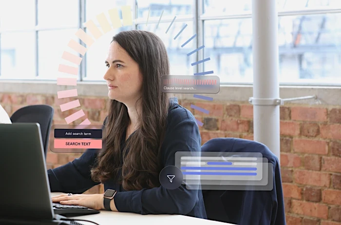 Legal professional working at a laptop in a brick-walled office, with visual overlays representing advanced legal search and clause-level analysis.