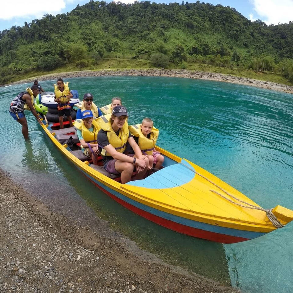 A group of ffriends in a yellow kayak wearing life jackets have just returned looking happy after a riverside cruise