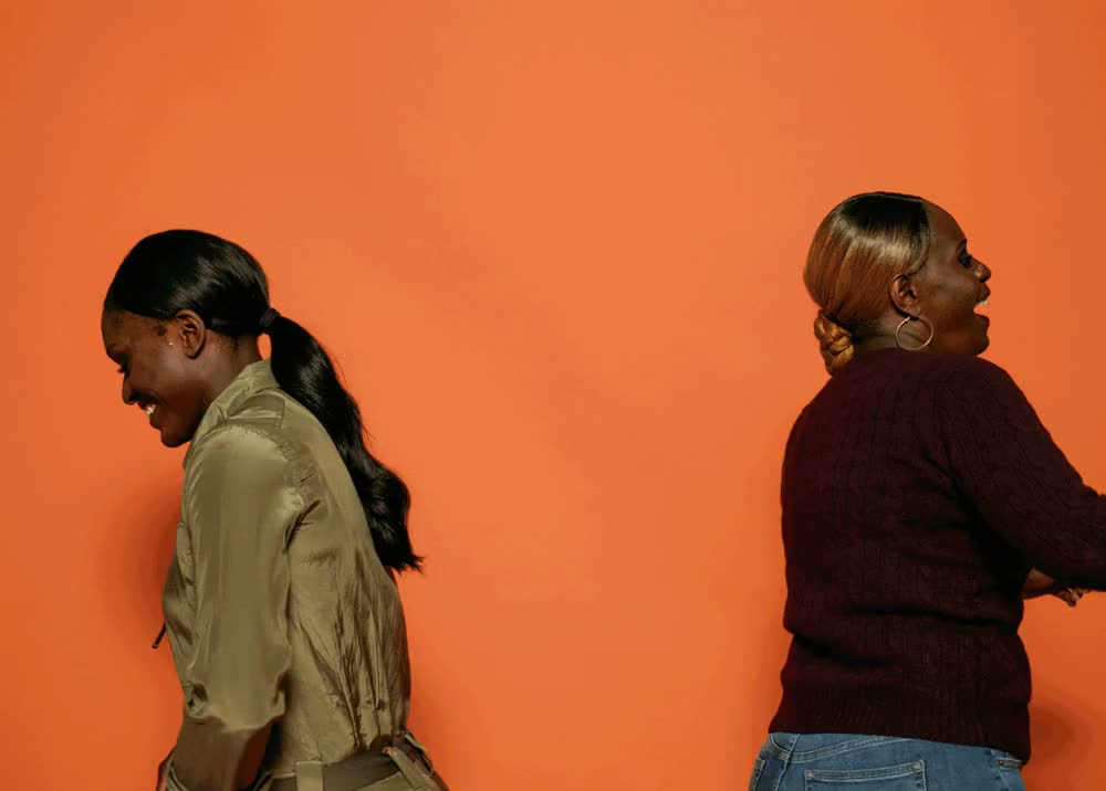 Aja Evans and her mother dancing together against an orange background