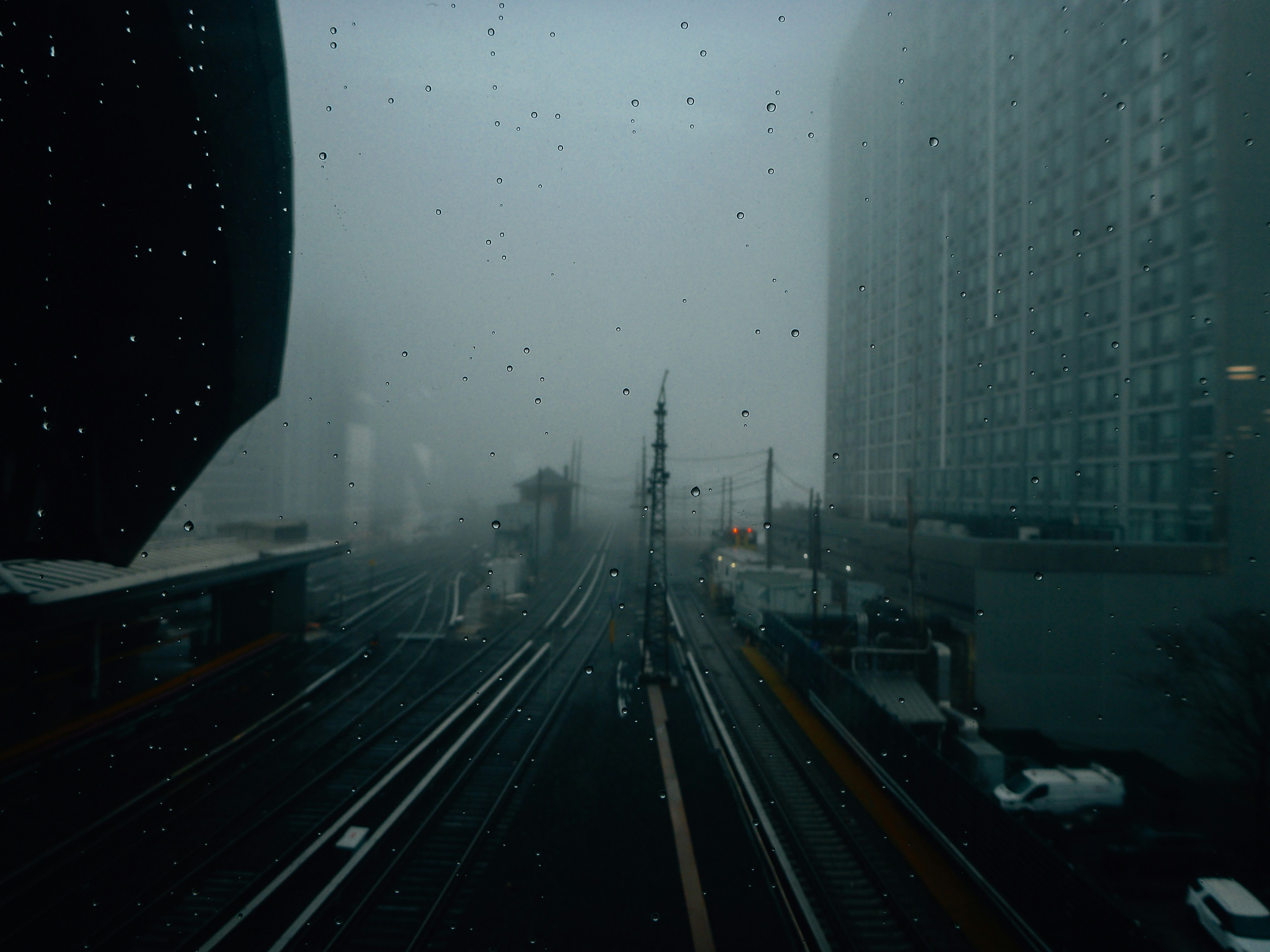 Rainy city street with train tracks and buildings