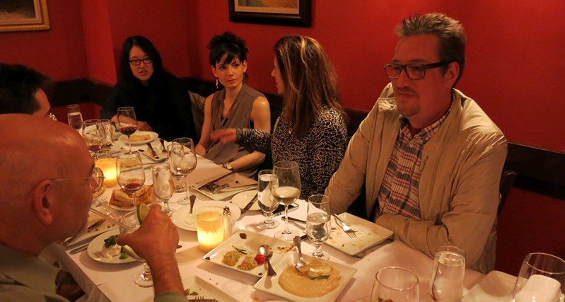 people gathered near a dinner table sitting and talking