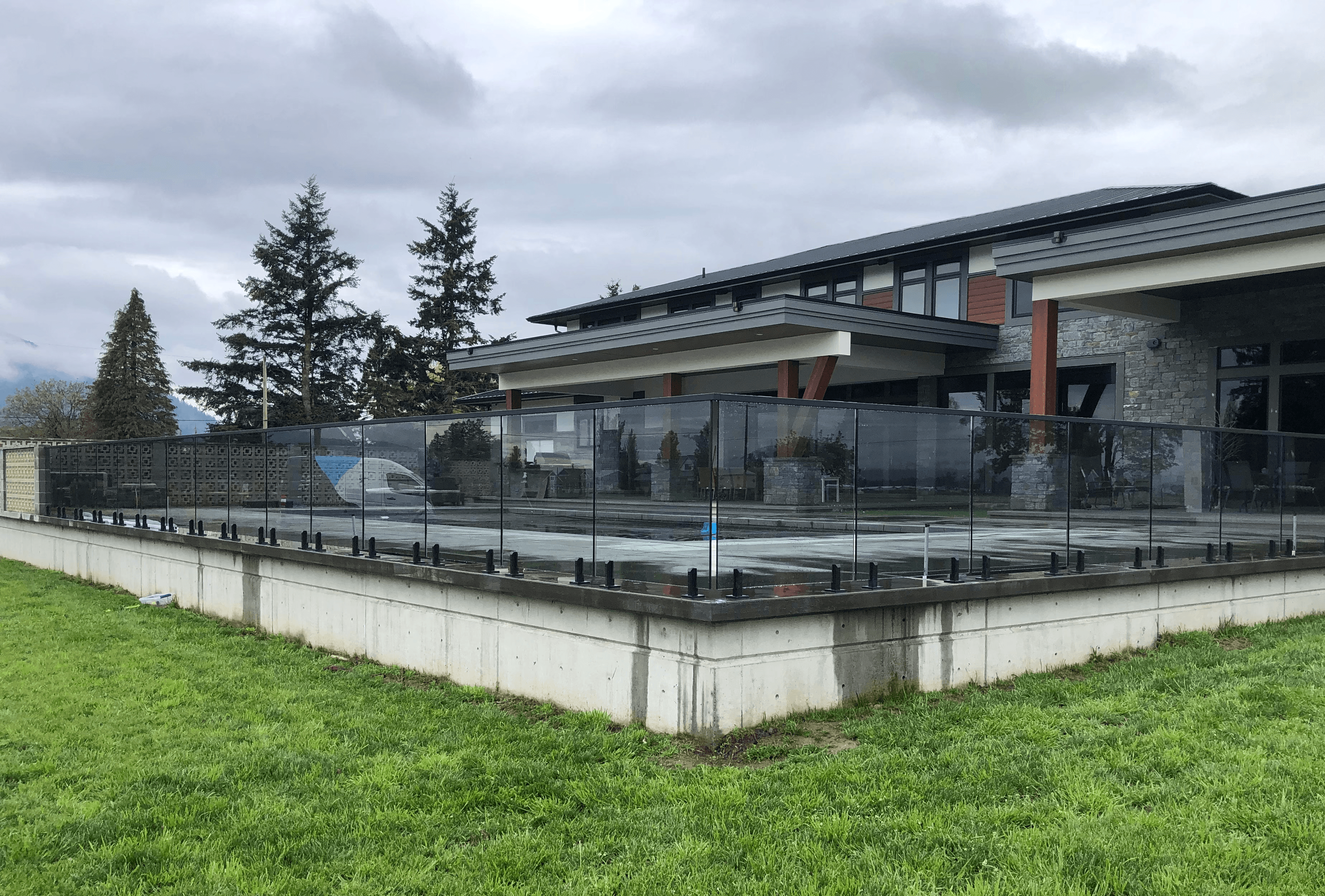 Custom patio glass railing layout surrounding a large modern outdoor terrace beside a contemporary luxury home.
