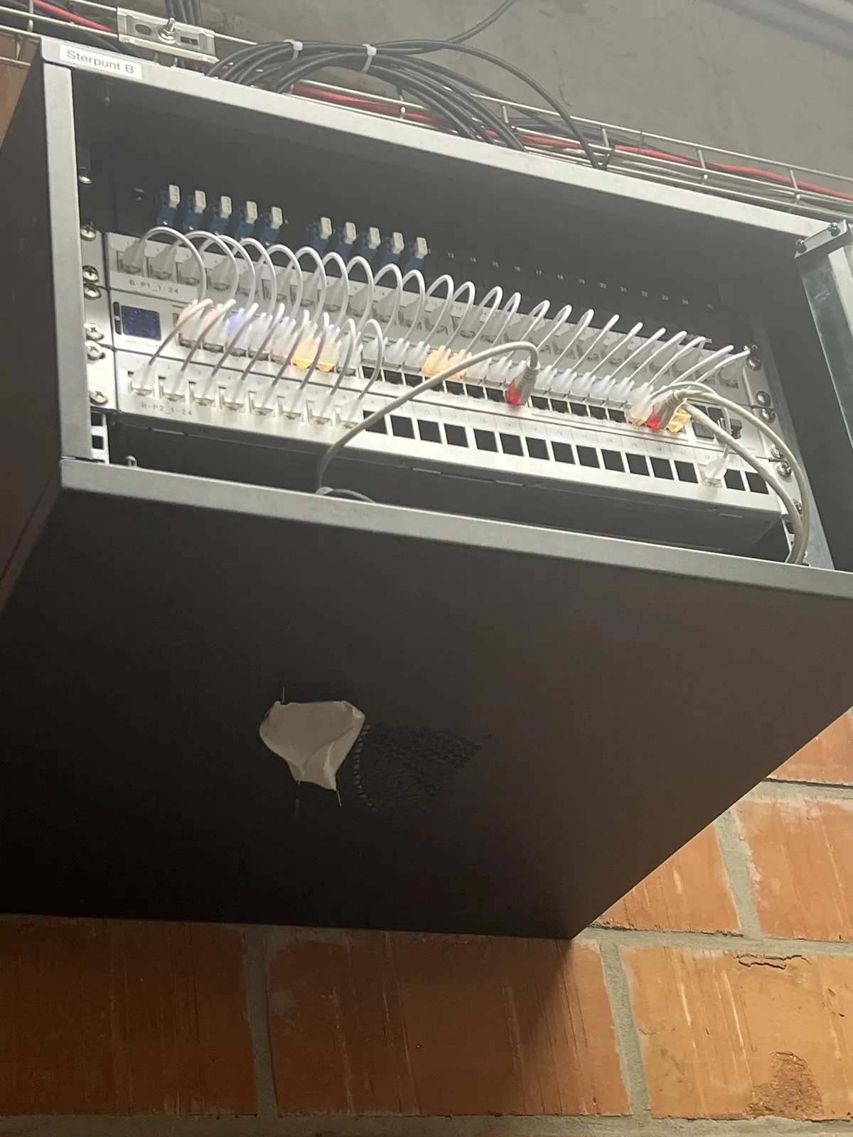 Wandkast met patchpanelen en netwerkbekabeling bij AAQUA