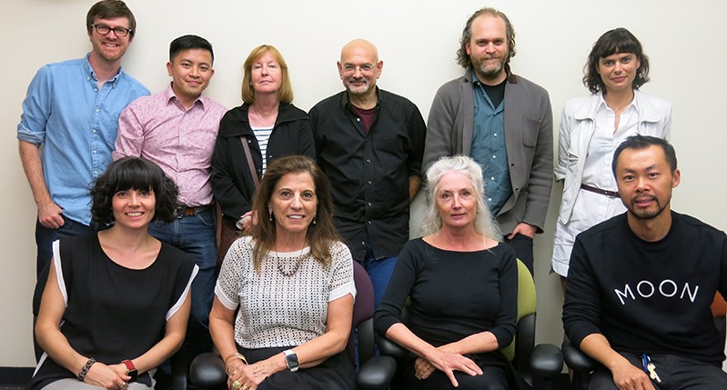 A photo of a group of people sitting in an exhibition room.