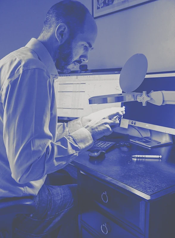 Product design engineer, Stuart Kelly inspecting prototype medical device component under magnification, illustrating hands on hardware development and testing process