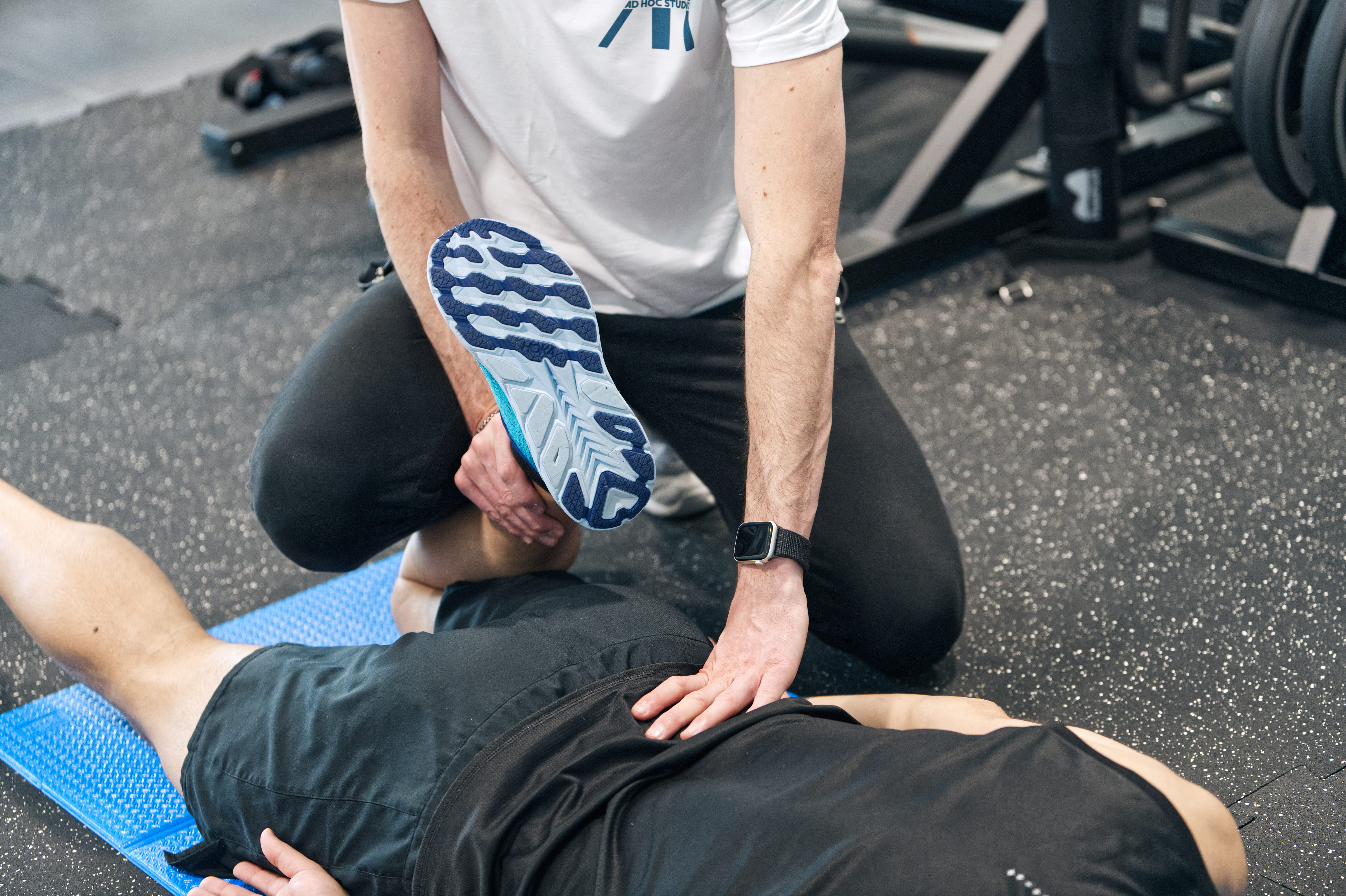 A man stands while two people sit at a table in an office setting, smiling and engaged in conversation. The mood is friendly and collaborative.