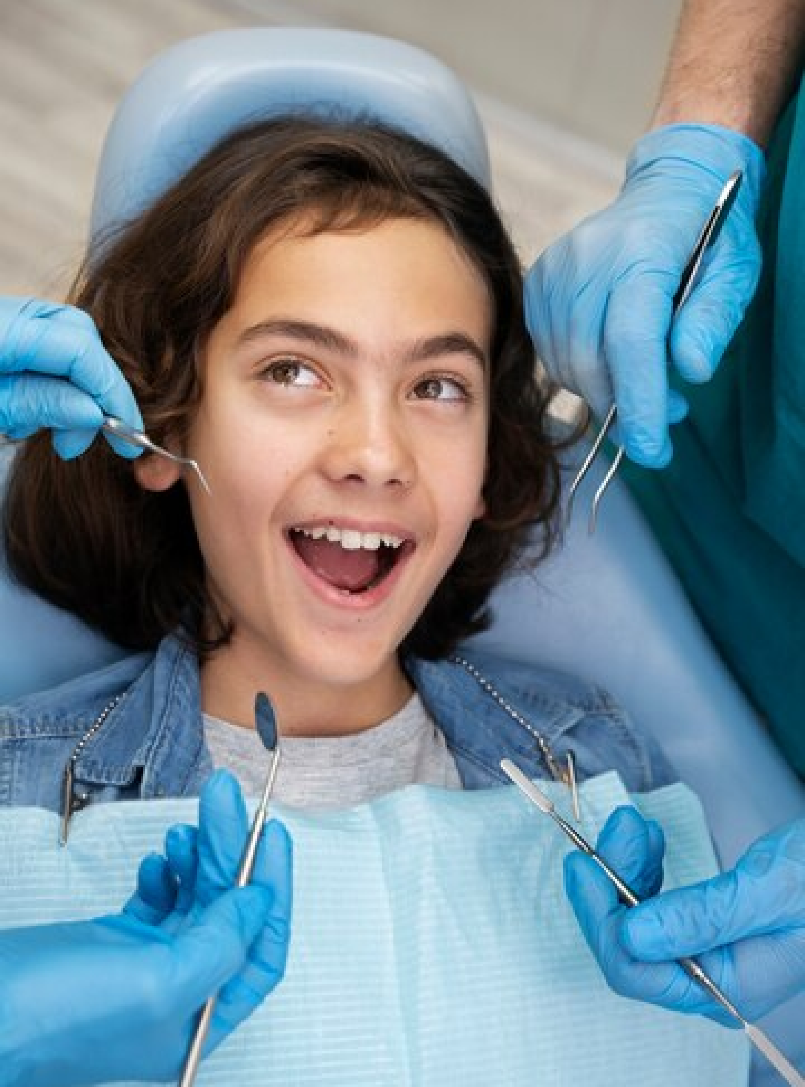 A young patient sitting in a dental chair, smiling and giving a thumbs up, indicating a positive dental experience