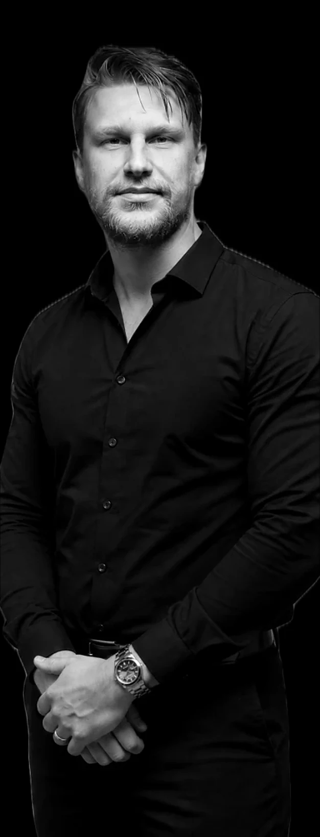 Kirill Samarits in a black shirt with his hands folded, black and white portrait