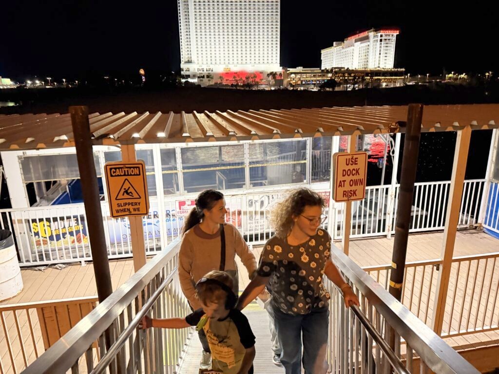 Family walking off the dock in Laughlin, Nevada at night with the casino skyline behind them