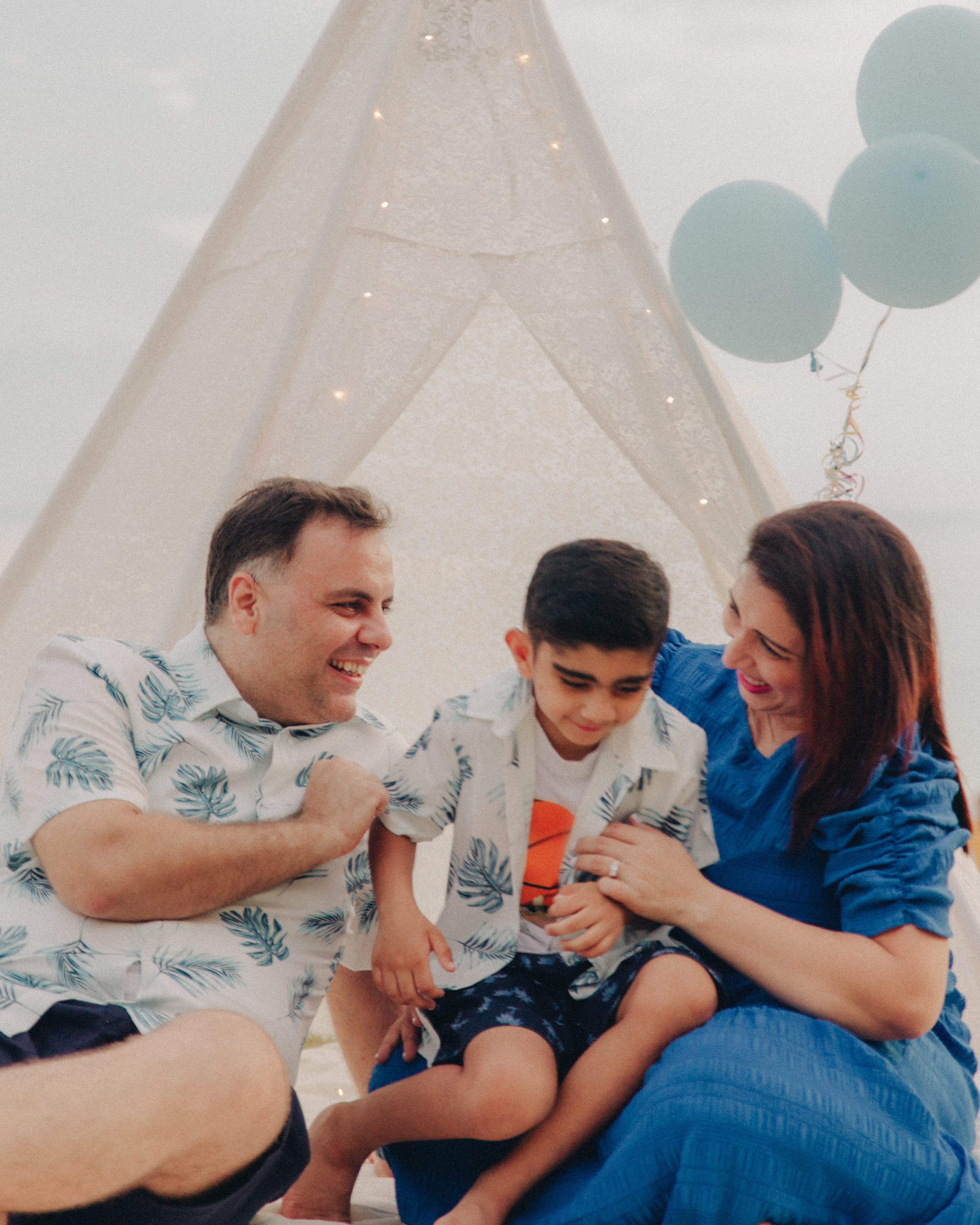 Family enjoying a quiet moment together near the sea at East Coast Park, neutral color palette.