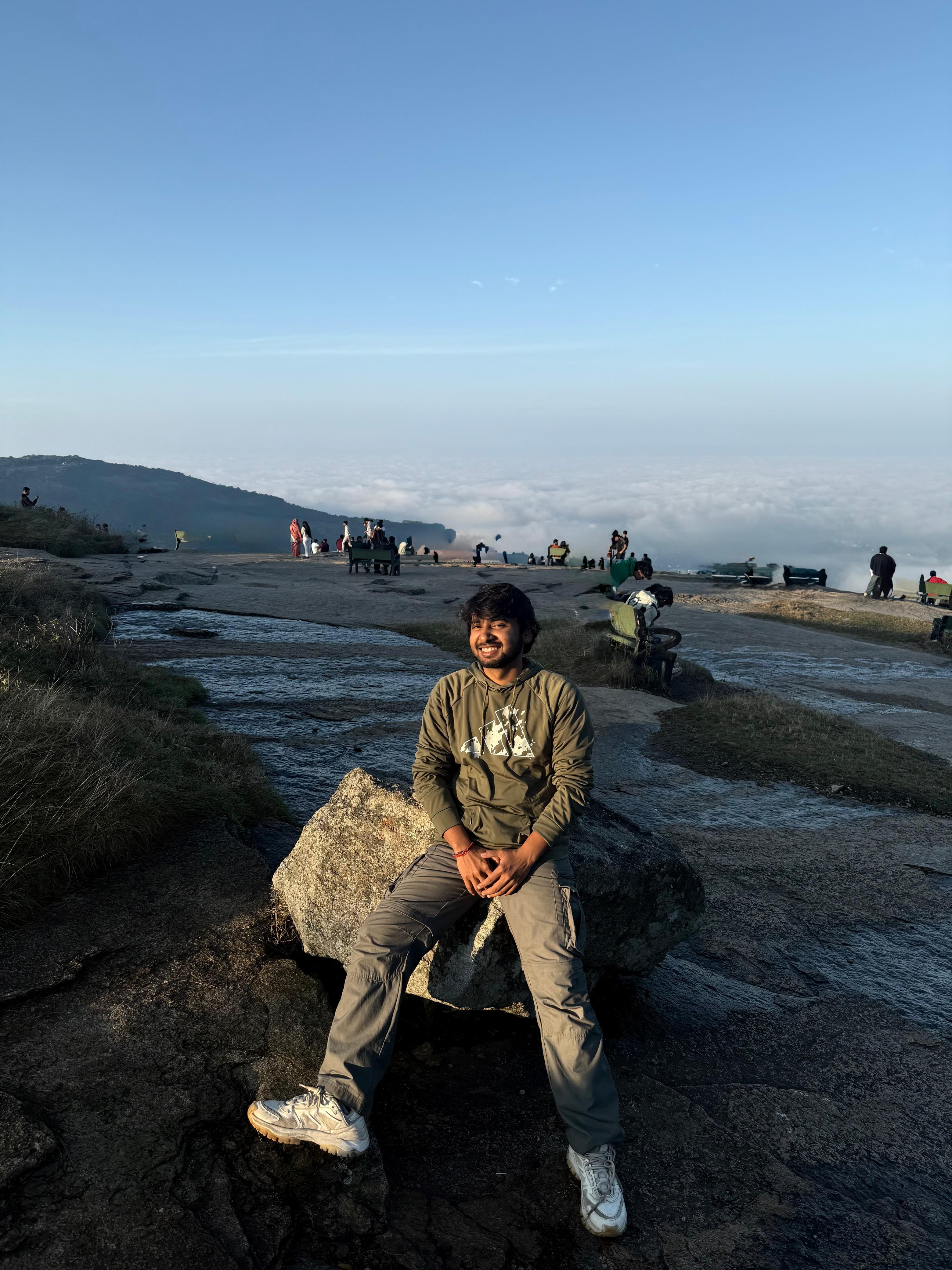 Man sitting in a dimly lit room, wearing a beige shirt and looking contemplative.