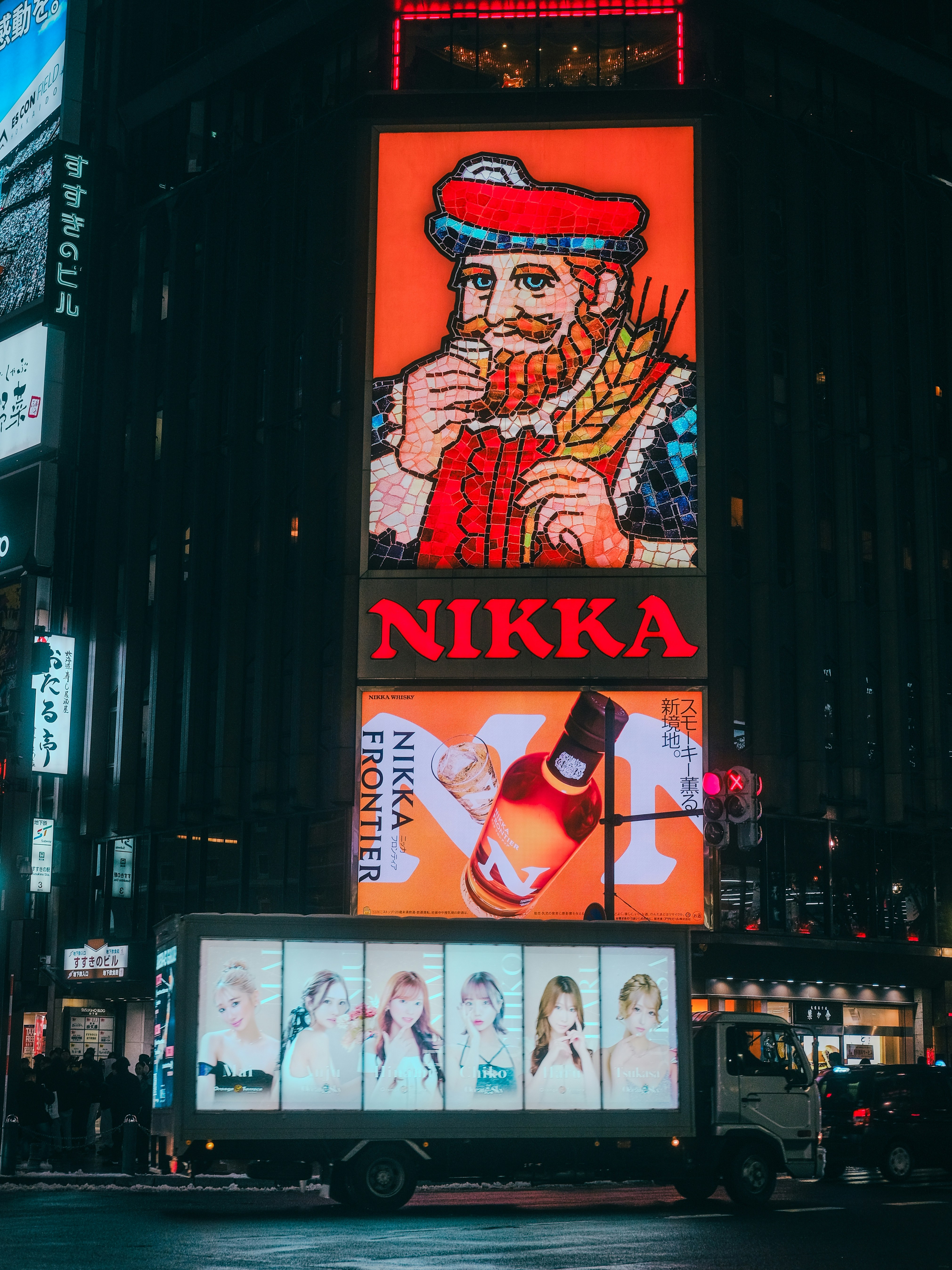 Neon signs illuminate a city street at night.