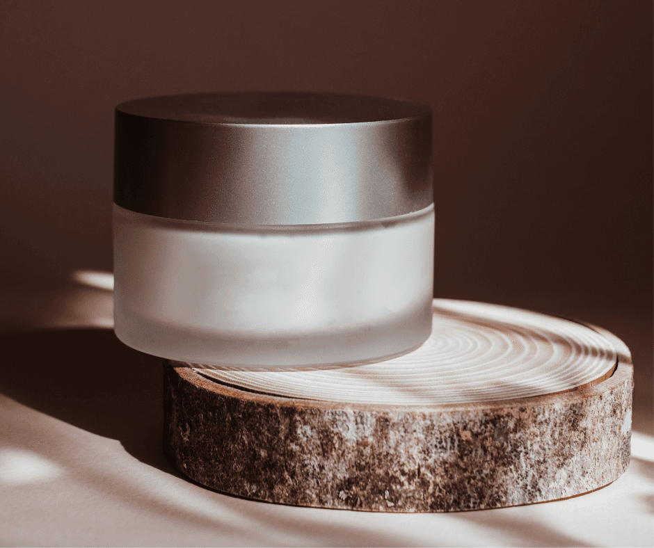 Minimalist frosted glass jar with matte black lid placed on a natural wood slice, capturing the intersection of refined aesthetics and nature-conscious cosmetic design.