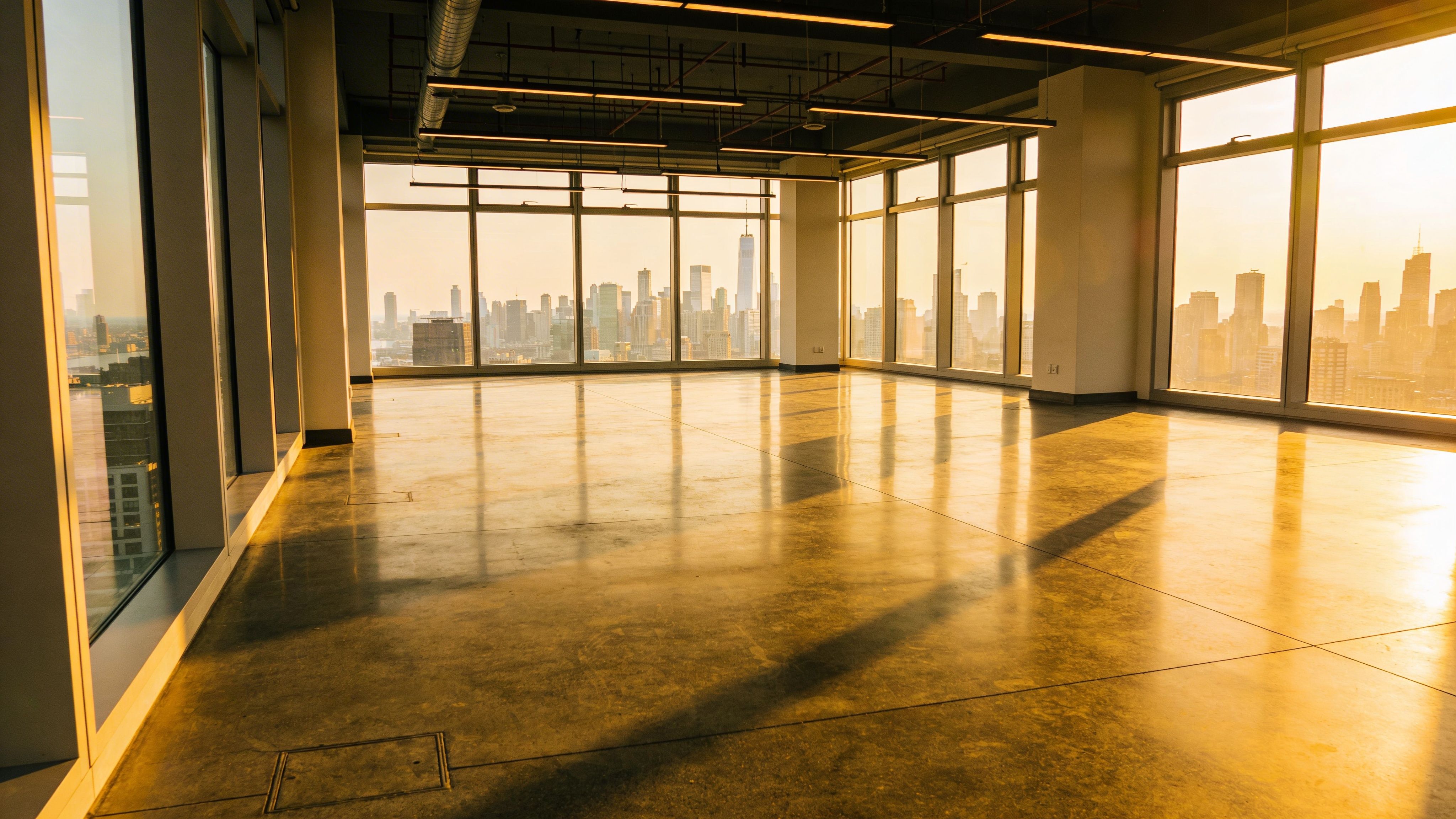 Sunlit empty office space with floor-to-ceiling windows and panoramic city skyline views